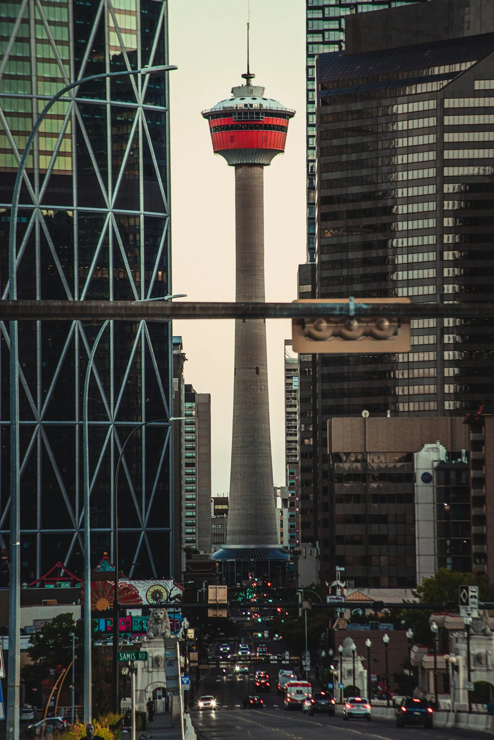 Downtown Calgary city streets with traffic, tall glass buildings, and Calgary Alberta's "Calgary Tower" in the background.
