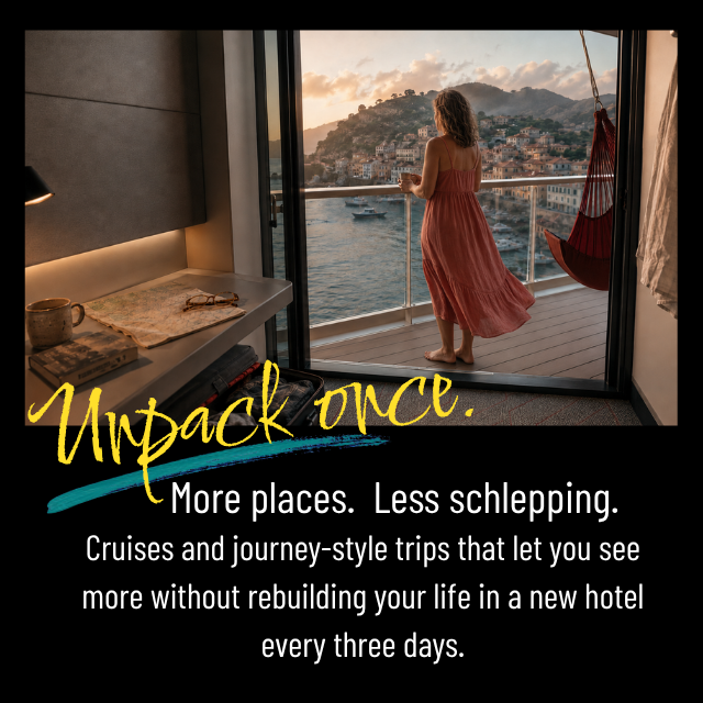 A woman in a pink dress looks out from a hotel balcony over a harbor with boats and hillside buildings at sunset.