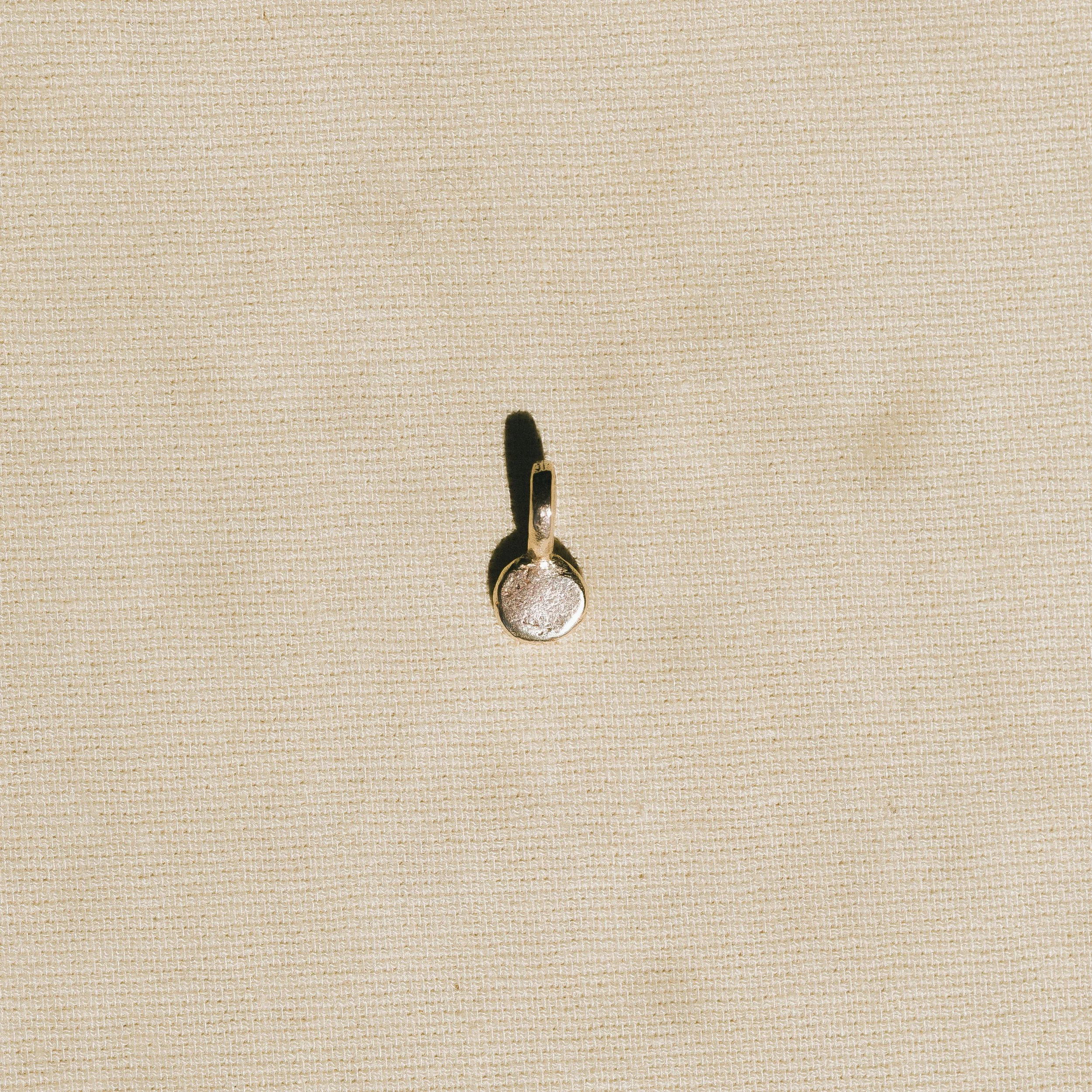 A metal spoon resting on a textured beige fabric surface.