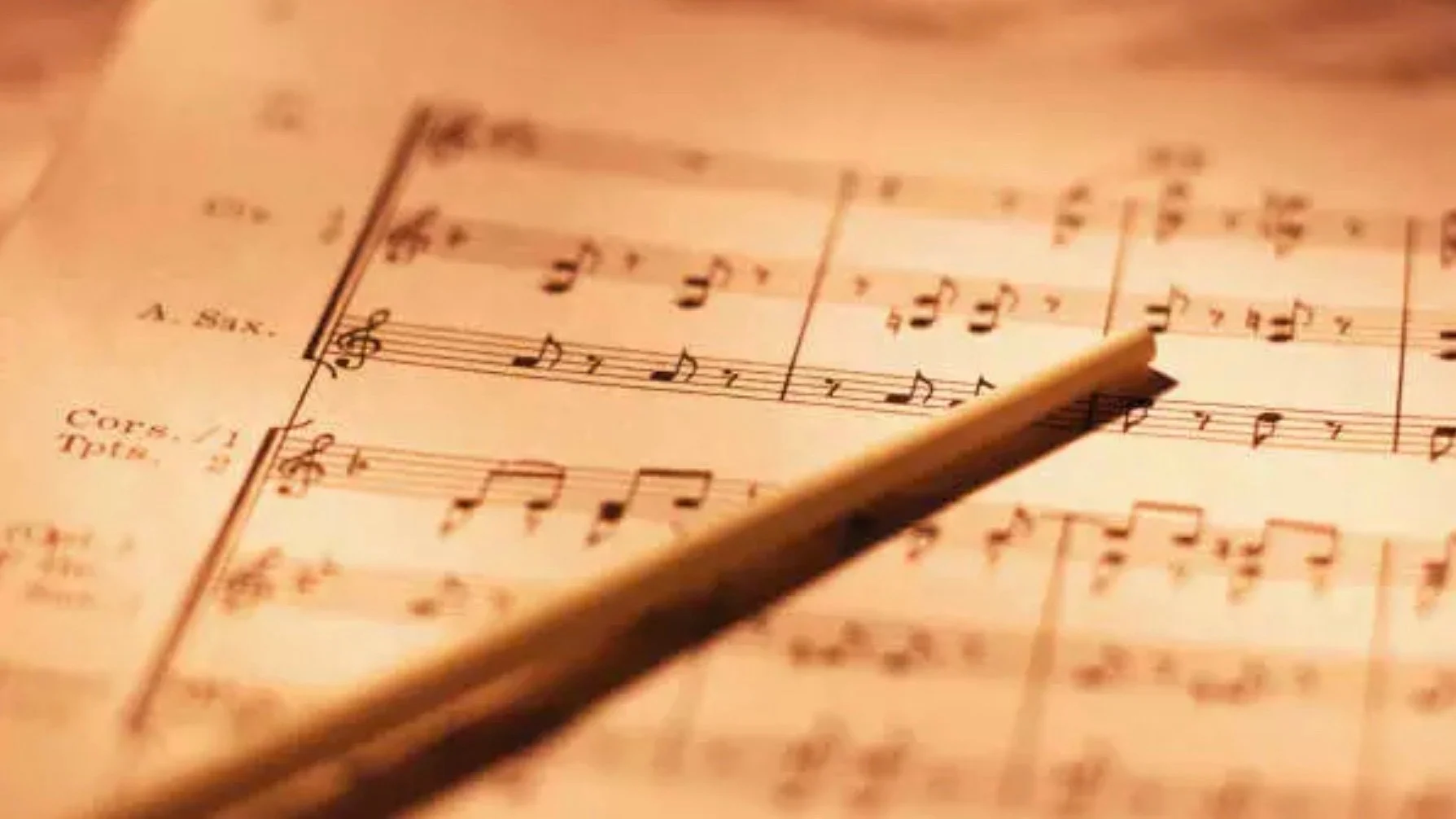 Sheet music with a conductor's baton resting on it.