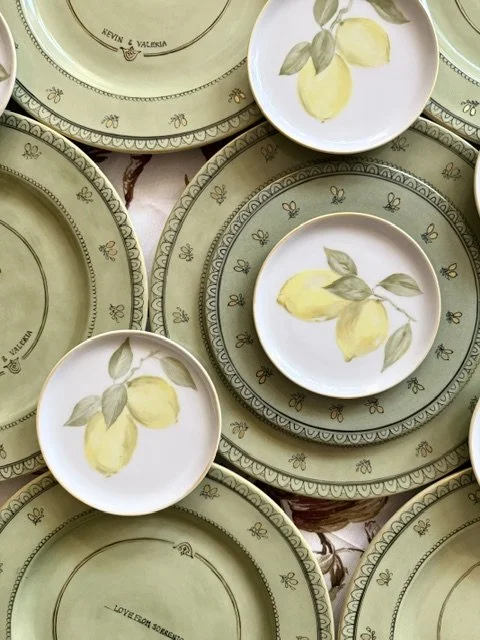 Array of ceramic plates with lemon and leaf designs and decorative borders.