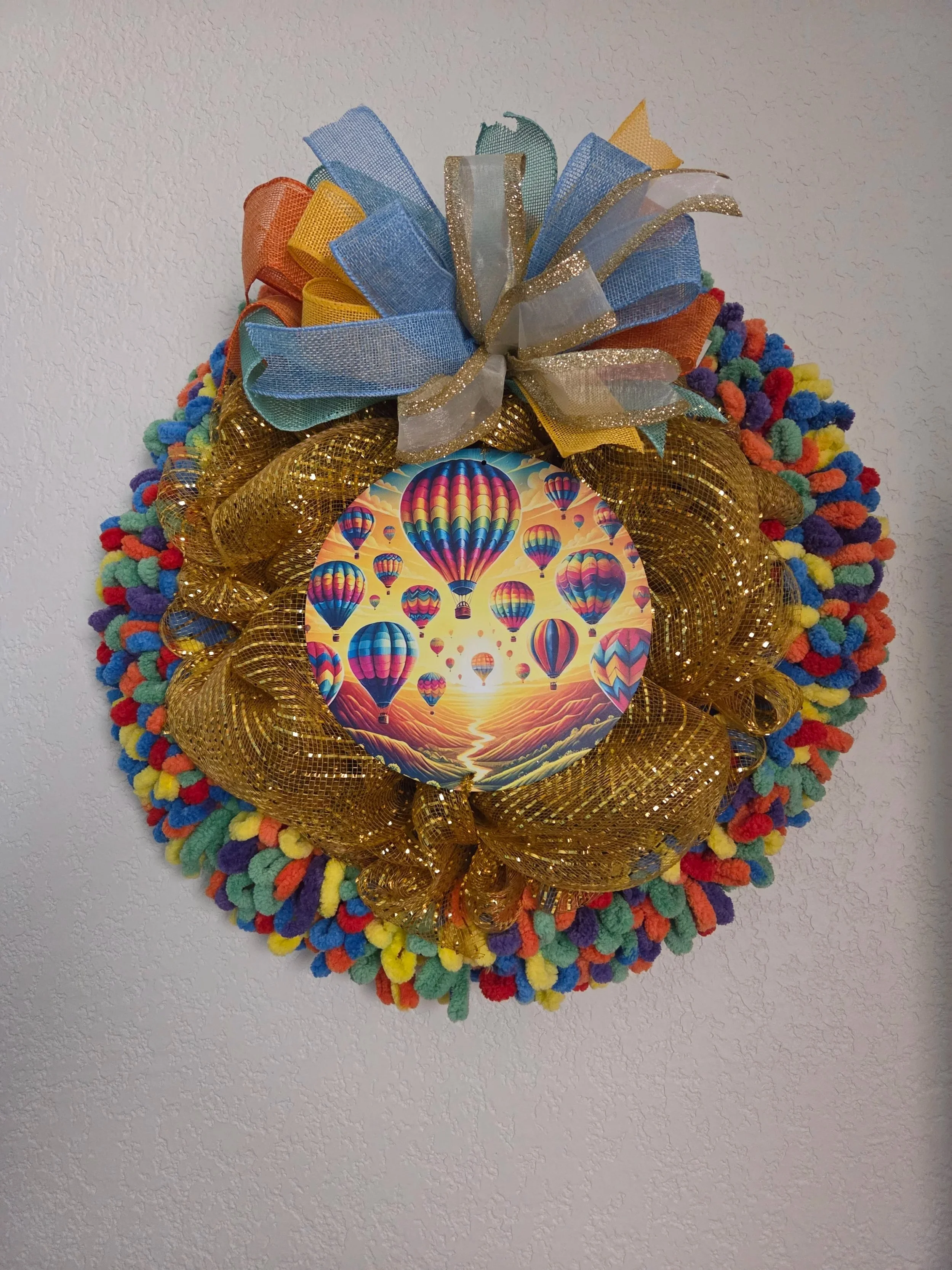 Colorful Easter wreath with a photo of hot air balloons at the center, adorned with a multicolored ribbon bow on top.