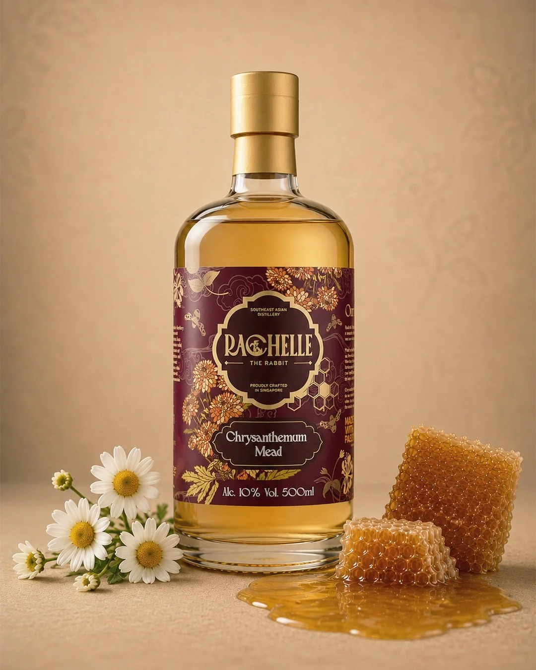 A bottle of Rochester the Rabbit Chrysanthemum Mead with honeycomb and daisies beside it on a beige background.