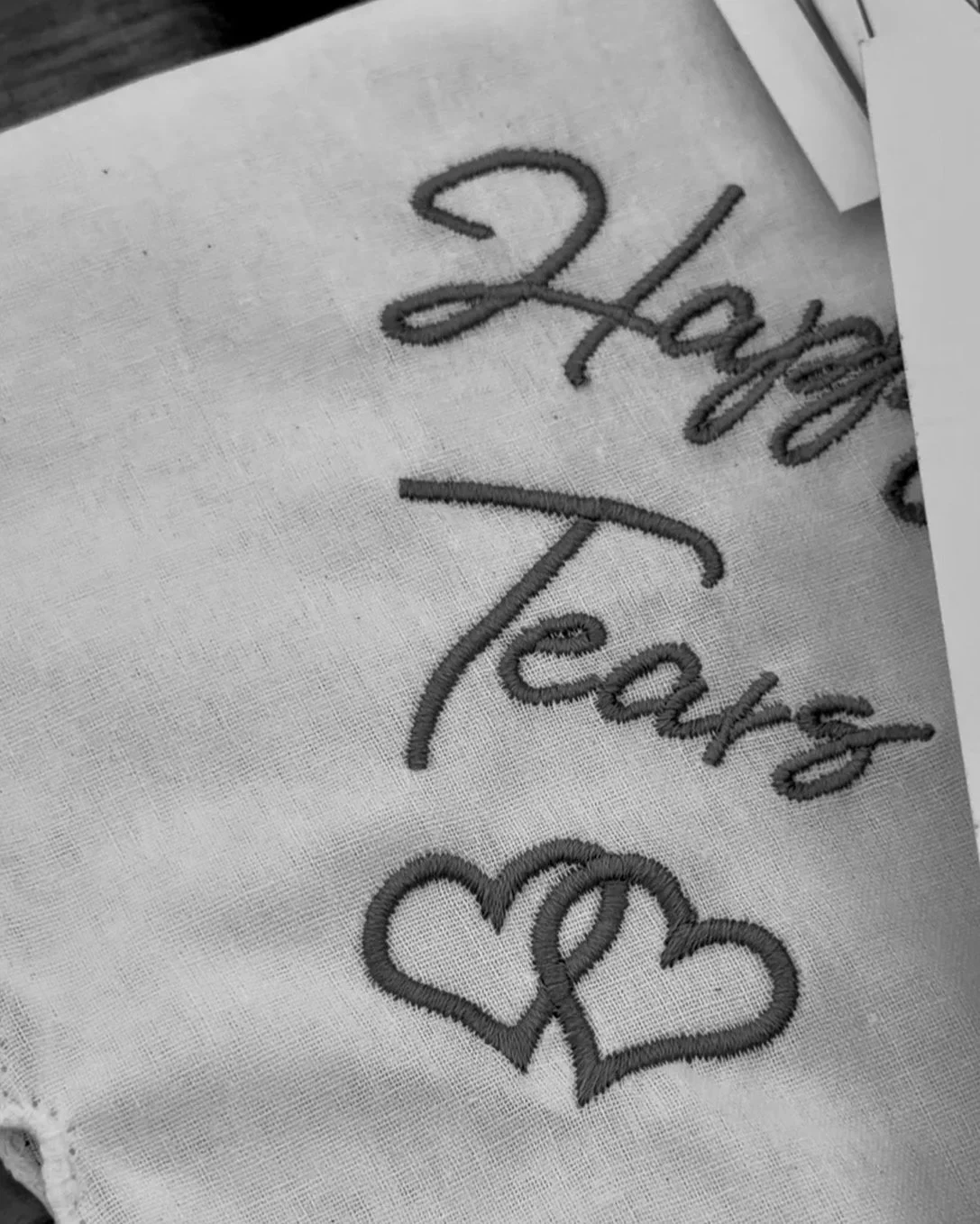 Embroidery on fabric with the words 'Happy Teacher' and two interlocking hearts.