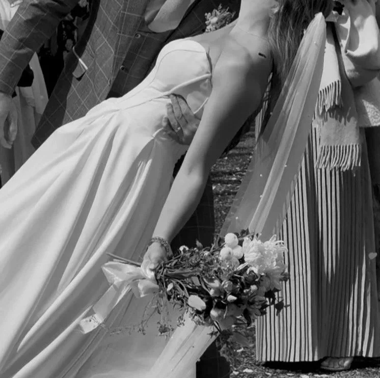A woman in a wedding dress holding a bouquet of flowers, partially visible in a black-and-white photograph.