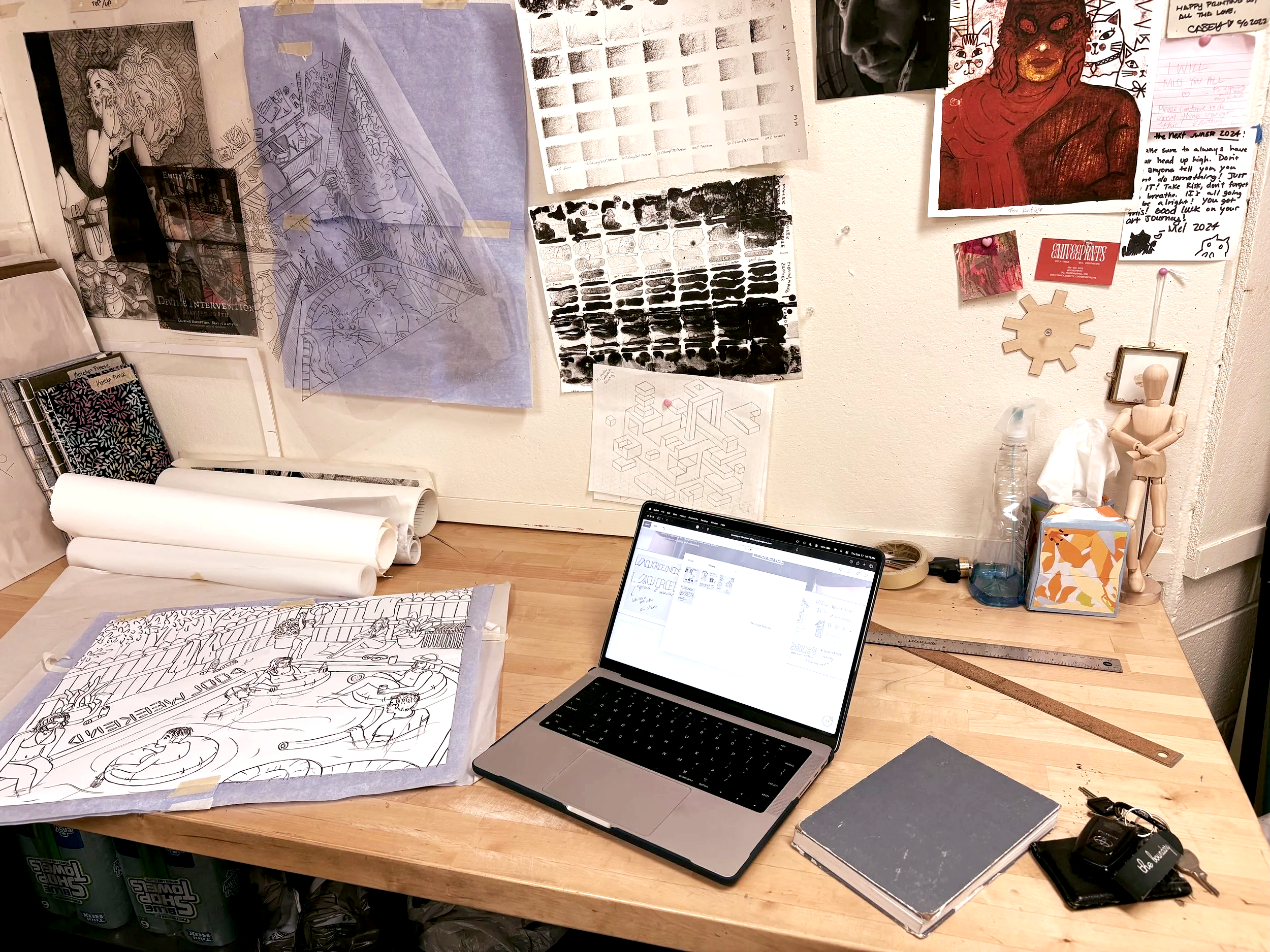 Artistic workspace with sketches, drawings, and a laptop on a wooden table, surrounded by various art supplies, notes, and posters on the wall.