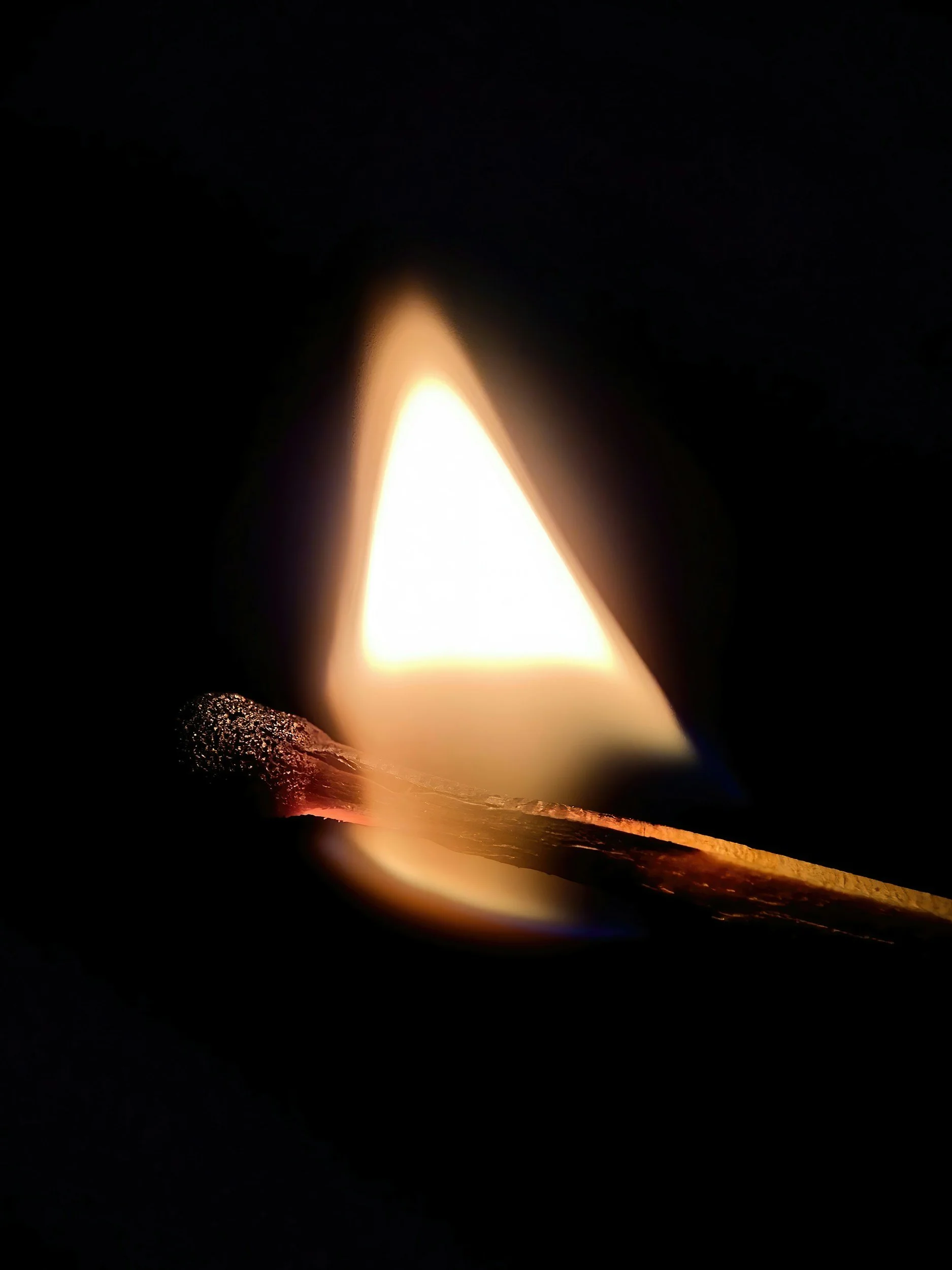 A matchstick igniting with a bright flame against a dark background.