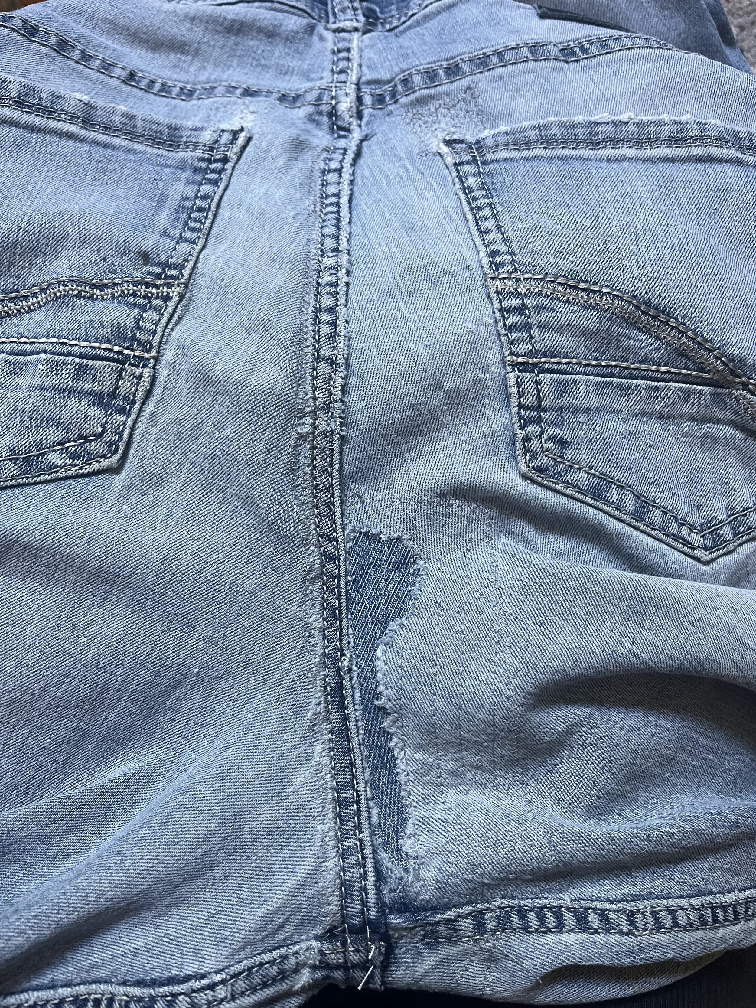 Close-up of the back of a person lying down, wearing light blue denim jeans with visible stitching and back pockets.
