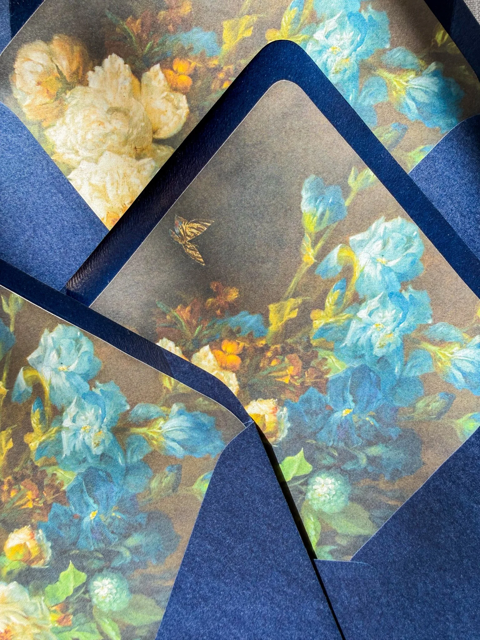 Close-up of an envelope liner with a floral painting design and a blue textured envelope.