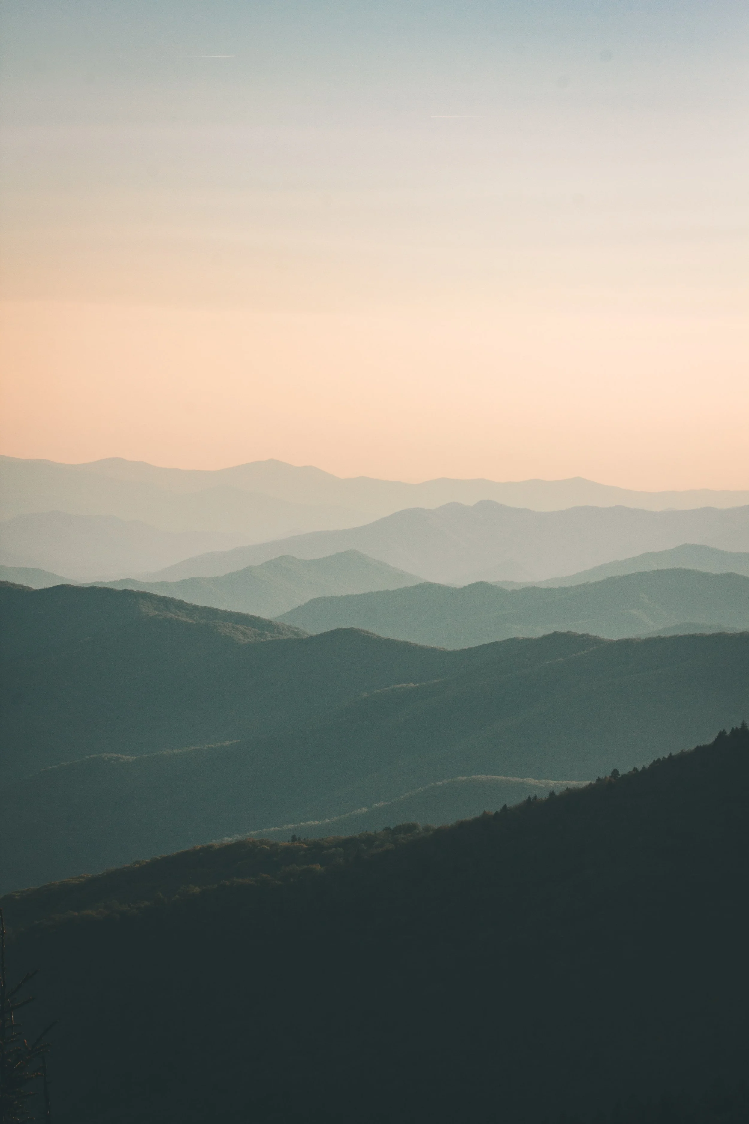 Layered mountain ranges at sunset with a pastel-colored sky.