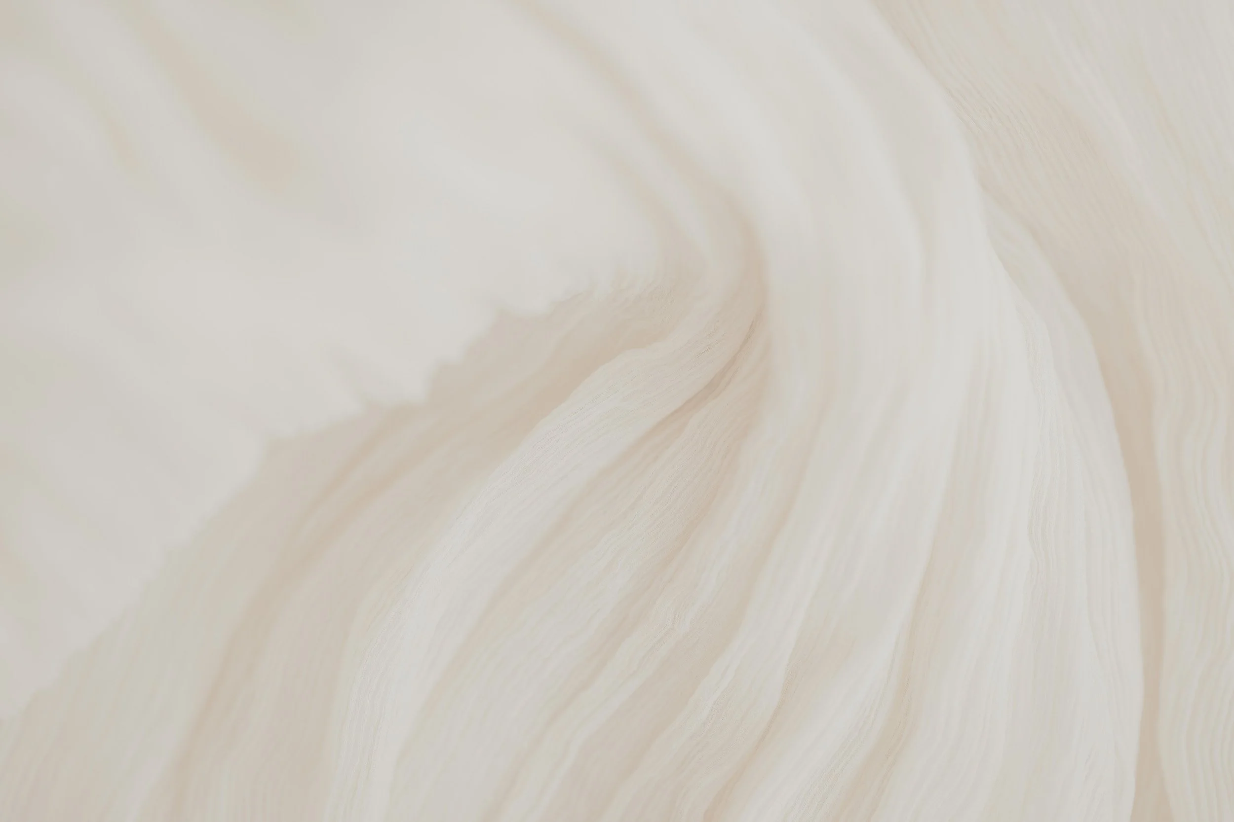 Close-up view of a light-colored, textured fabric with soft folds.