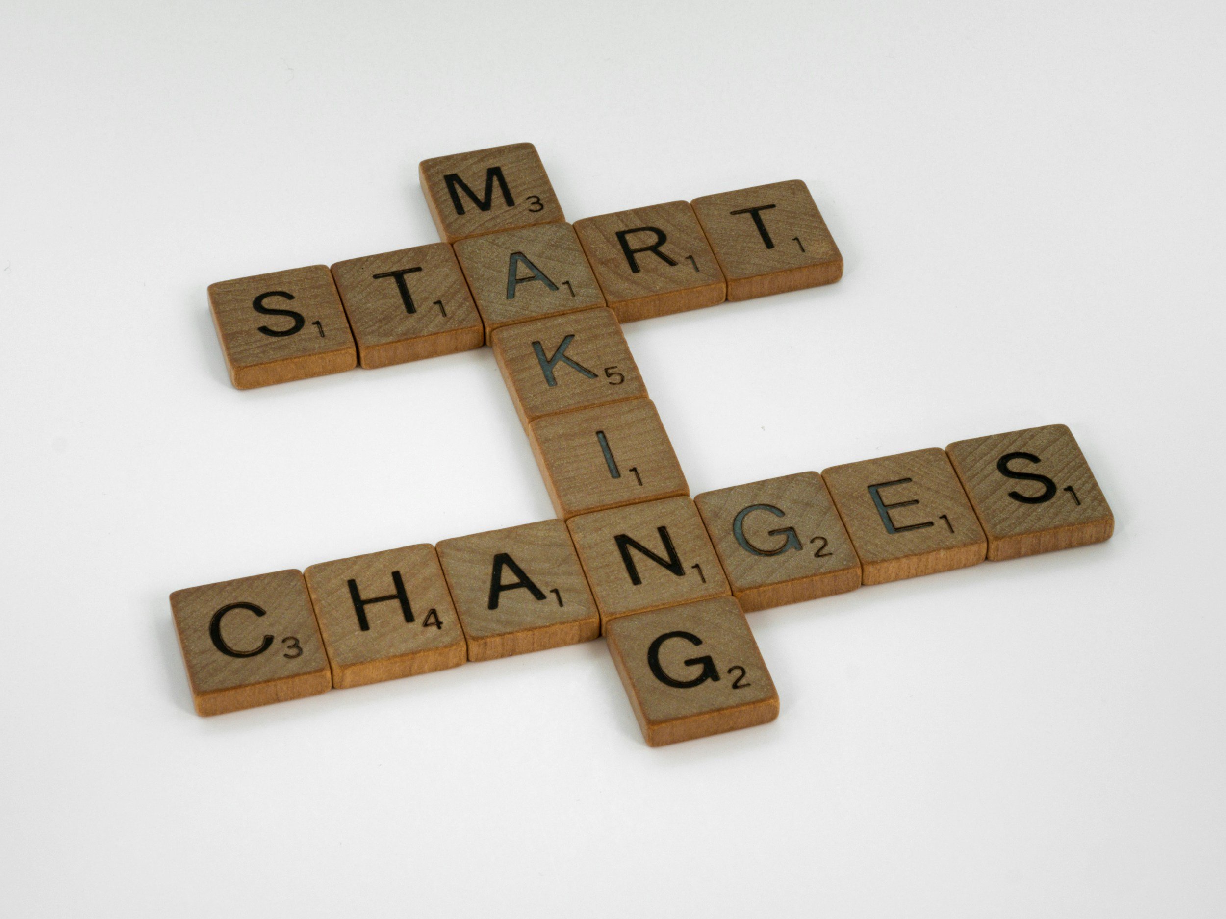 Close-up of wooden Scrabble tiles spelling out the word 'SMART' in the shape of a cross, with additional tiles around it on a white background.