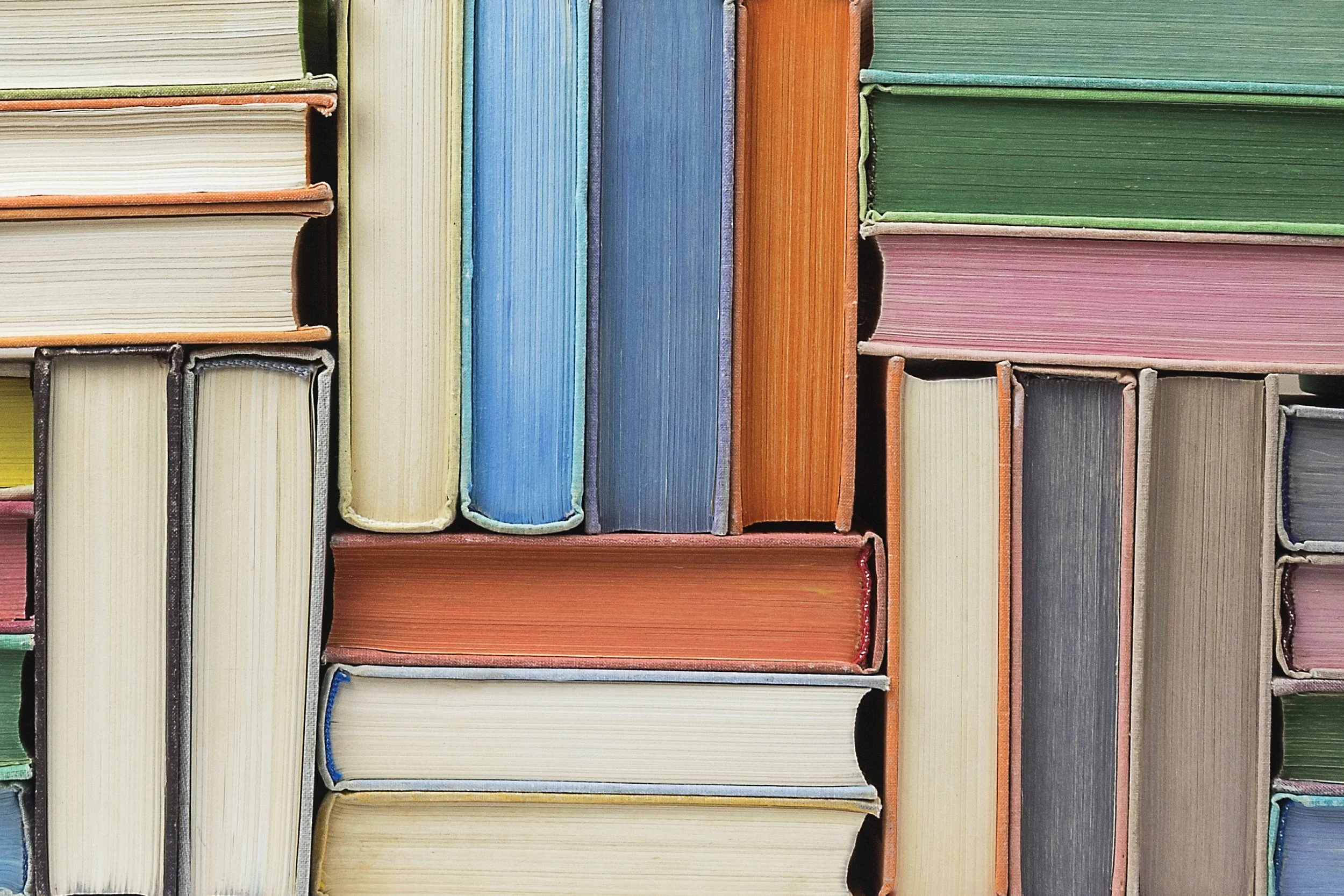 Close-up of colorful books placed vertically on a shelf, showing their spines.