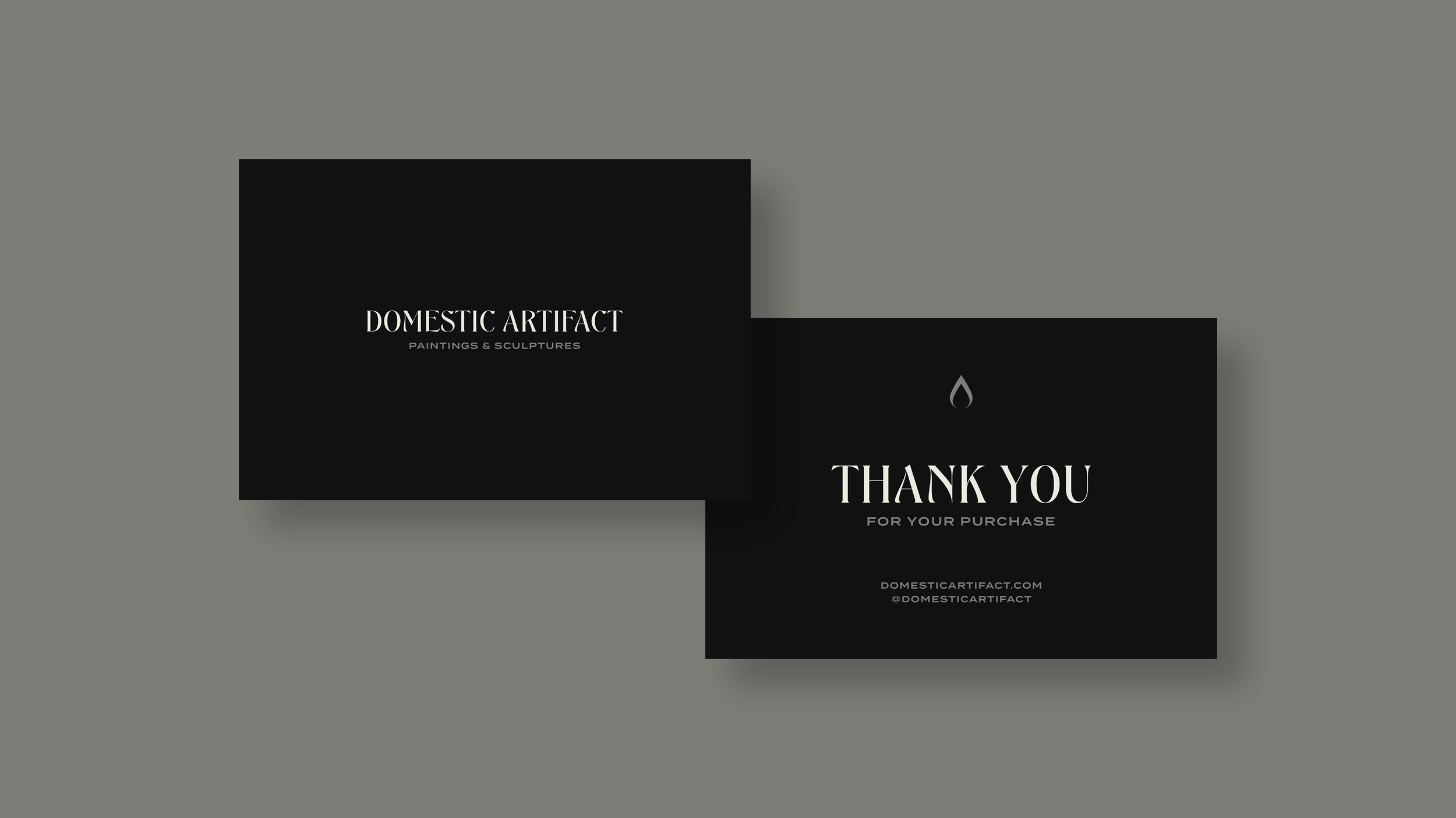 Black gift card with white text reading "Domestic Artifact Paintings & Sculptures" and a black thank you card with a water droplet icon and the text "Thank you for your purchase" on a gray background.