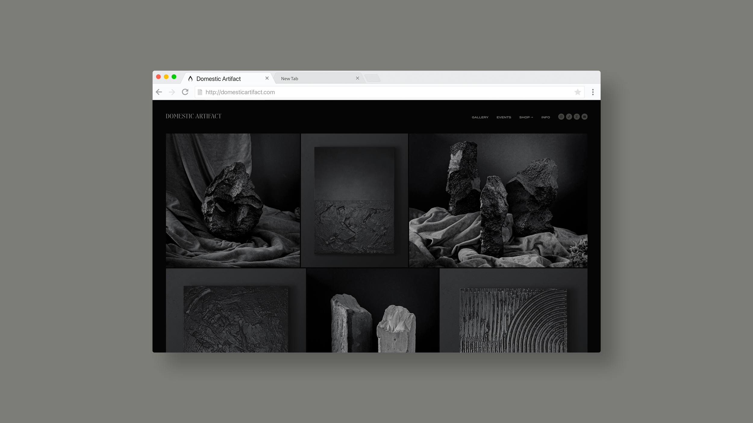 Black and white art display featuring various textured stone sculptures and abstract art pieces on a draped fabric background.
