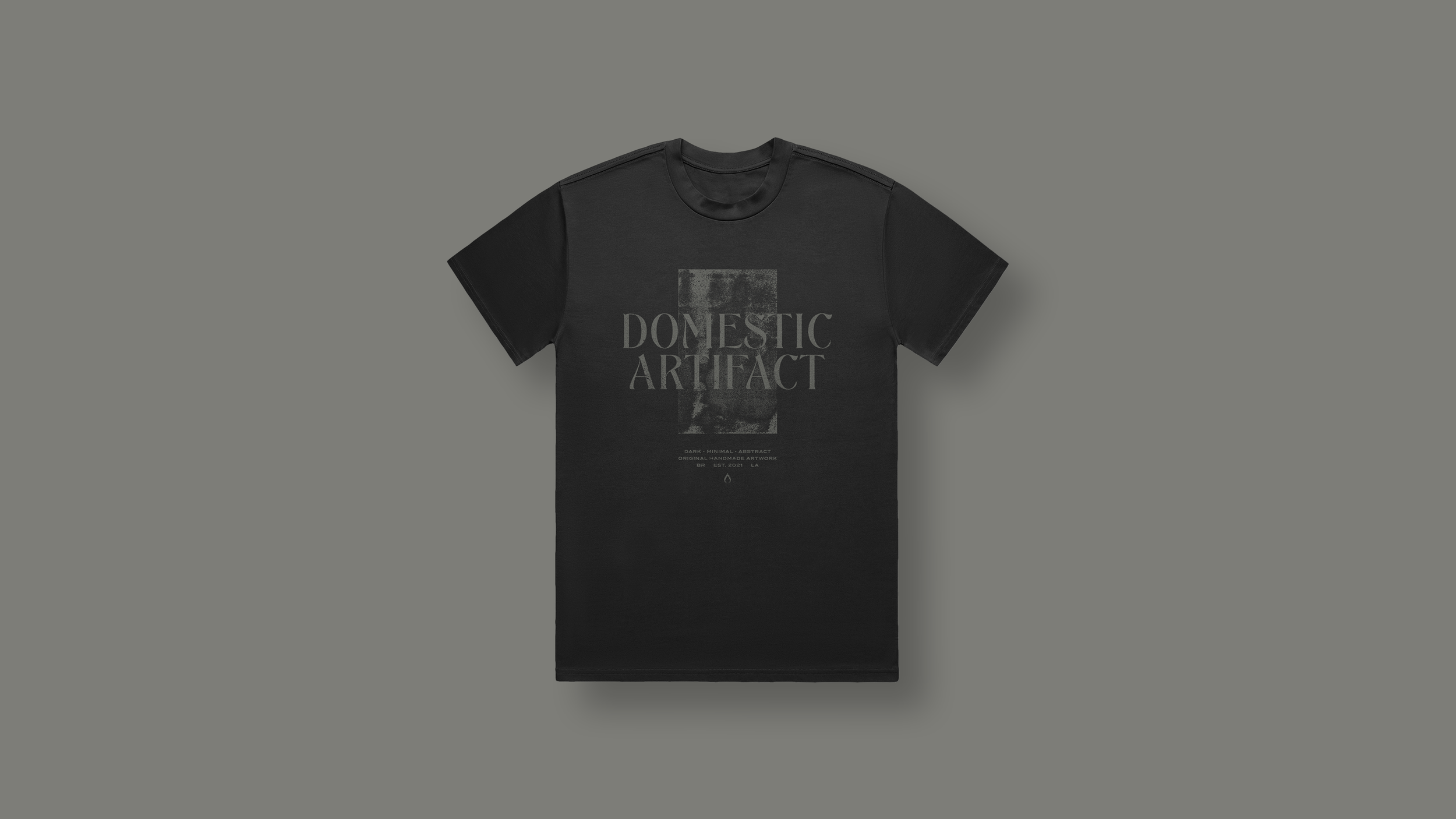 Black t-shirt with a distressed grey rectangle and the words "Domestic Artifact" printed on the front.