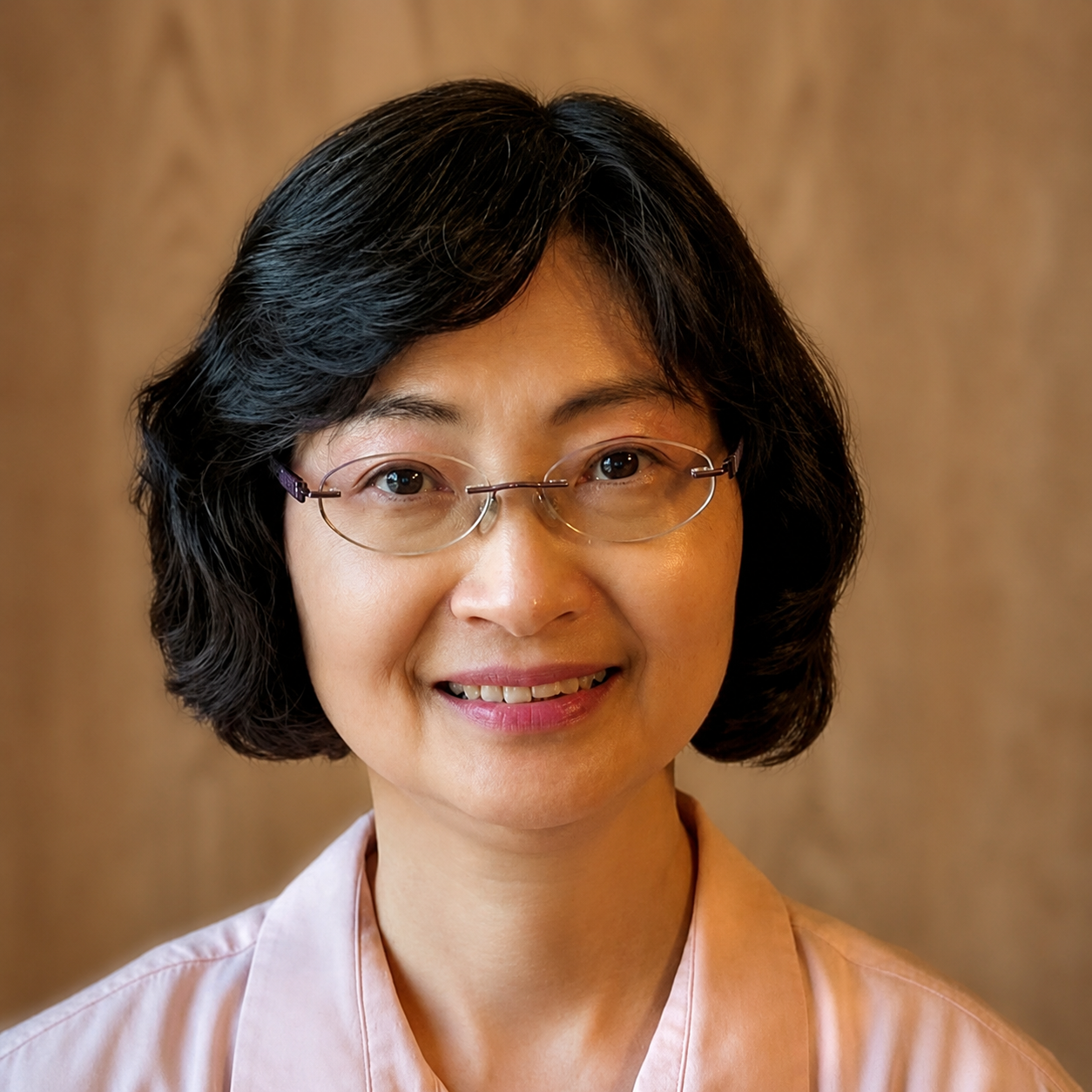 A professional clinical psychologist with short black hair and glasses, smiling at the camera against a neutral background.