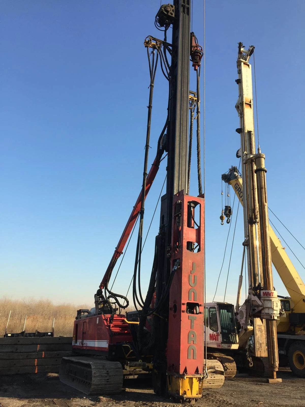 Construction drilling rig equipment on a construction site with a clear blue sky in the background.