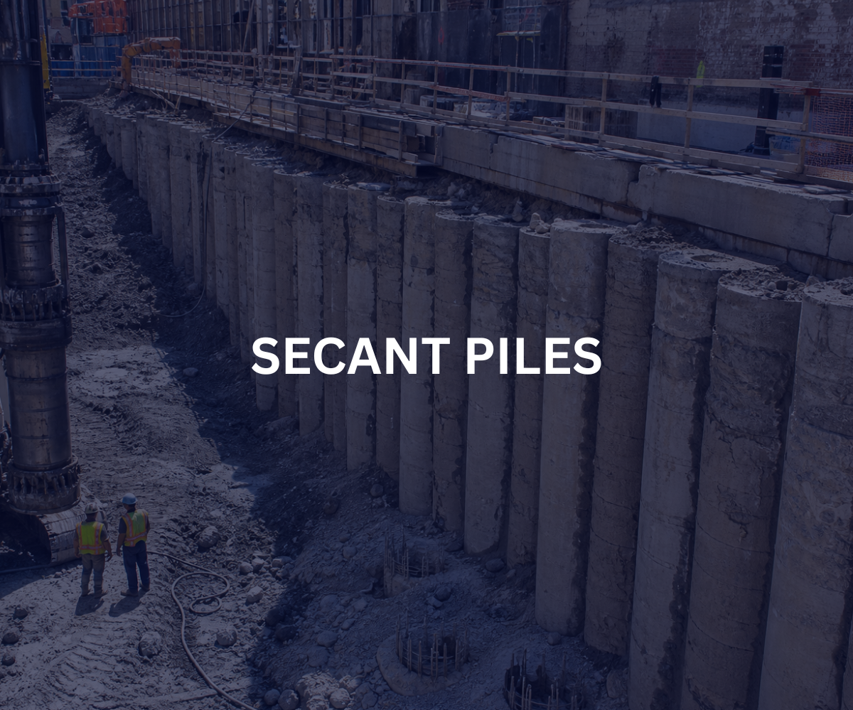 Construction site with large concrete piles and workers in safety gear.
