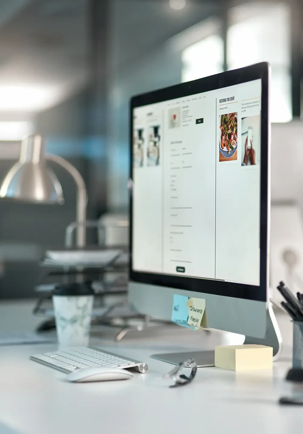 computer monitor with website on a desk with papers and a coffee cup in a cubicle .