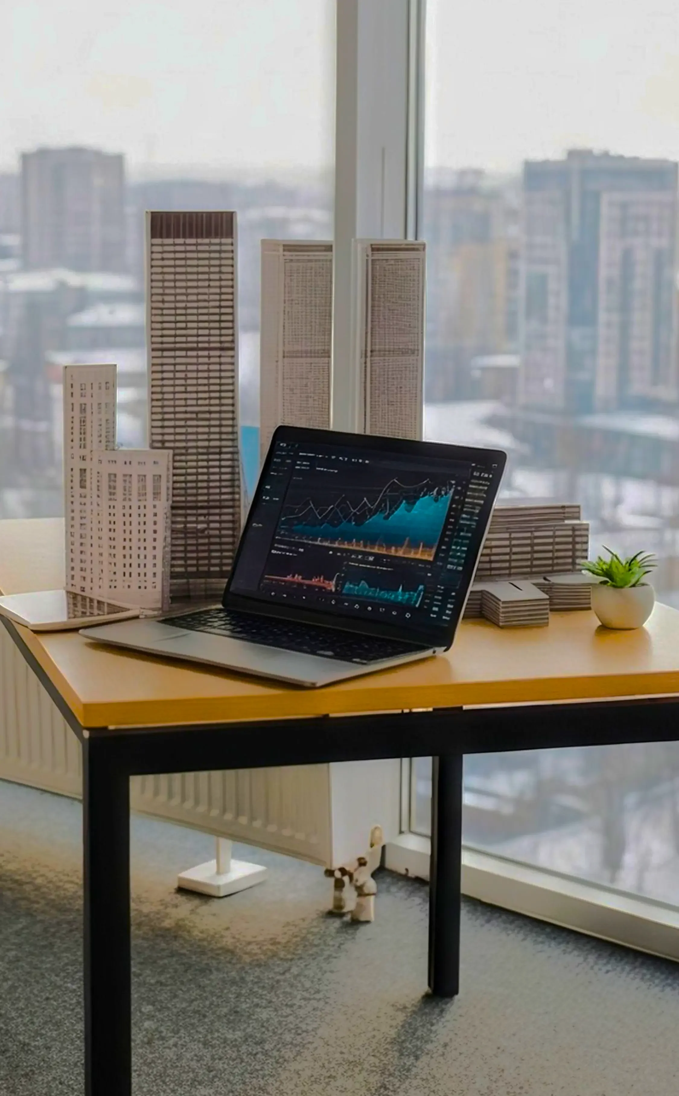 a computer on desk with grow chart on screen with surrounding skyscrapers