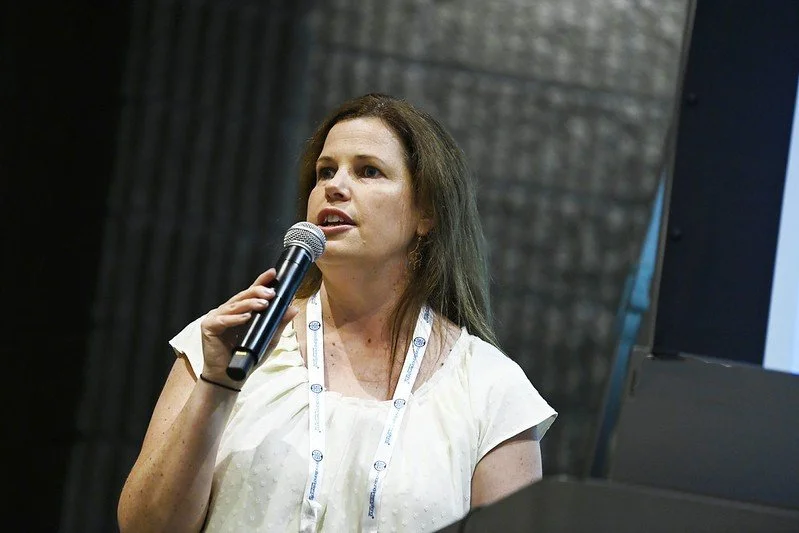 Woman speaking into a microphone during a presentation or conference.