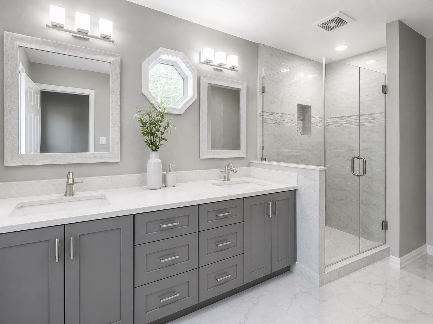 Modern bathroom with double vanity, gray cabinets, white countertop, two mirrors, and a glass-enclosed shower with marble tiles.