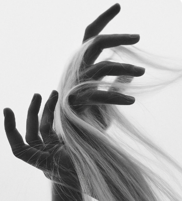 Black hands holding and flowing through long blonde hair.