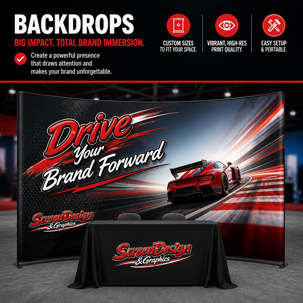 A large curved backdrop with racing graphics and a red sports car, displaying the text "Drive Your Brand Forward" and "ScreenDesign & Graphics." In front of the backdrop, there is a table covered with a black cloth featuring the ScreenDesign & Graphics logo.