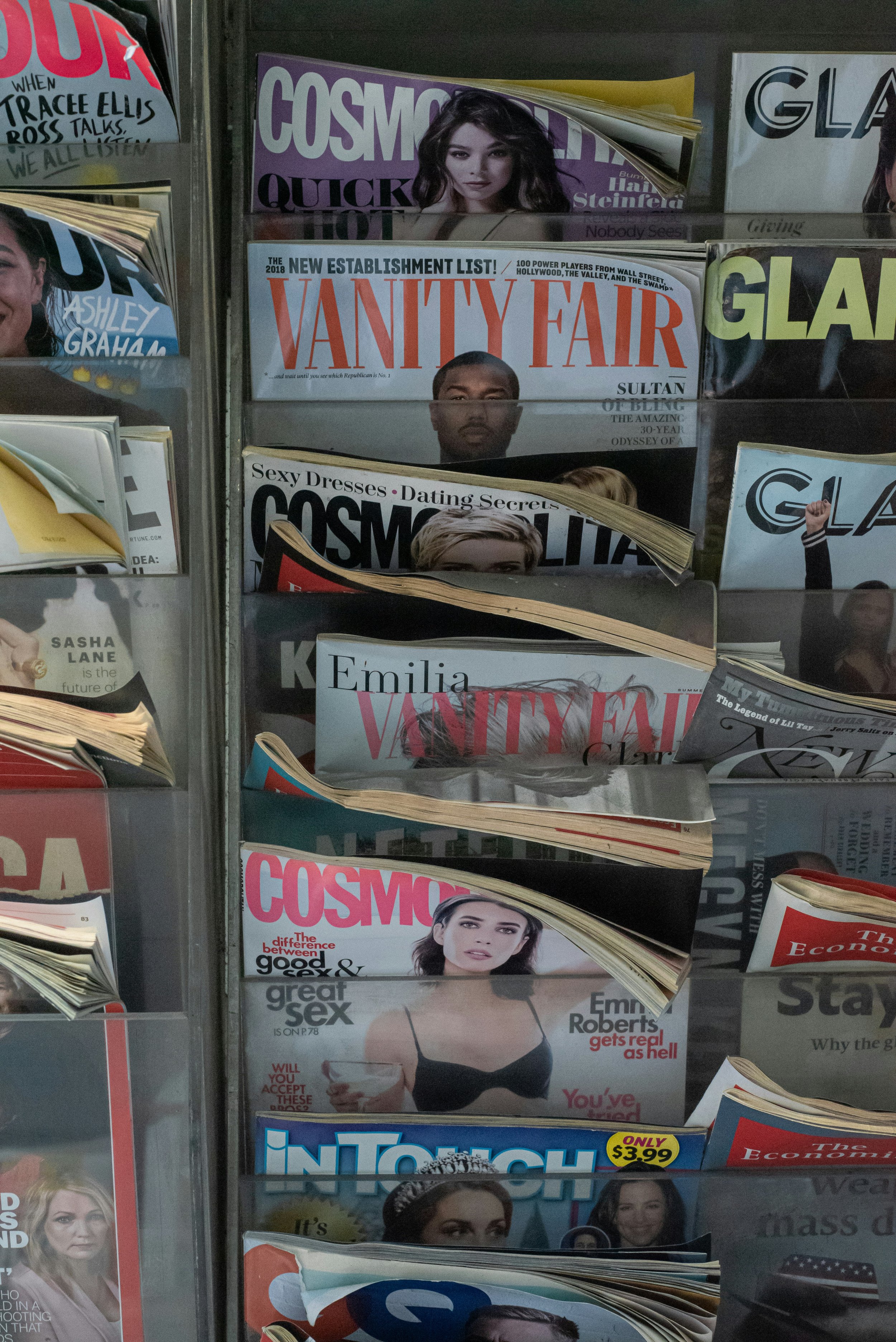 A magazine rack with multiple magazines including Vanity Fair, Cosmopolitan, Glamour, In Touch, and other publications featuring celebrity covers and articles.