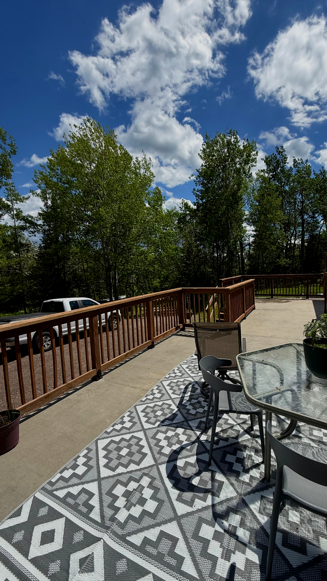 An outdoor concrete patio that's elevated about 5 feet off the ground. It has a cedar tone pressure treated wood railing along the perimeter with vertical spindles.