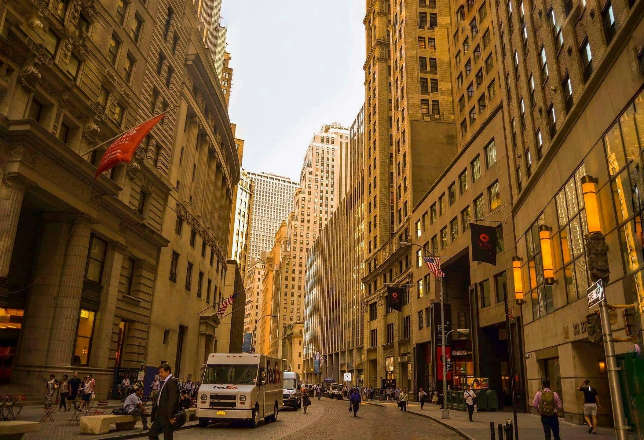 City street with tall buildings, people walking, and a FedEx delivery truck.