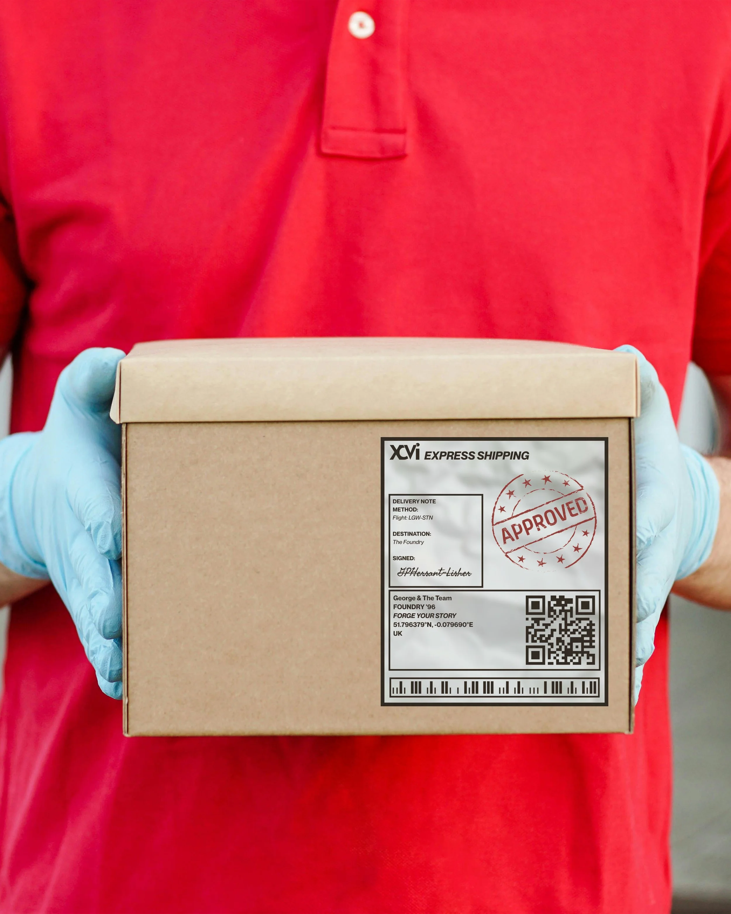 Person wearing a red shirt and blue gloves holding a cardboard box with a shipping label on the front.