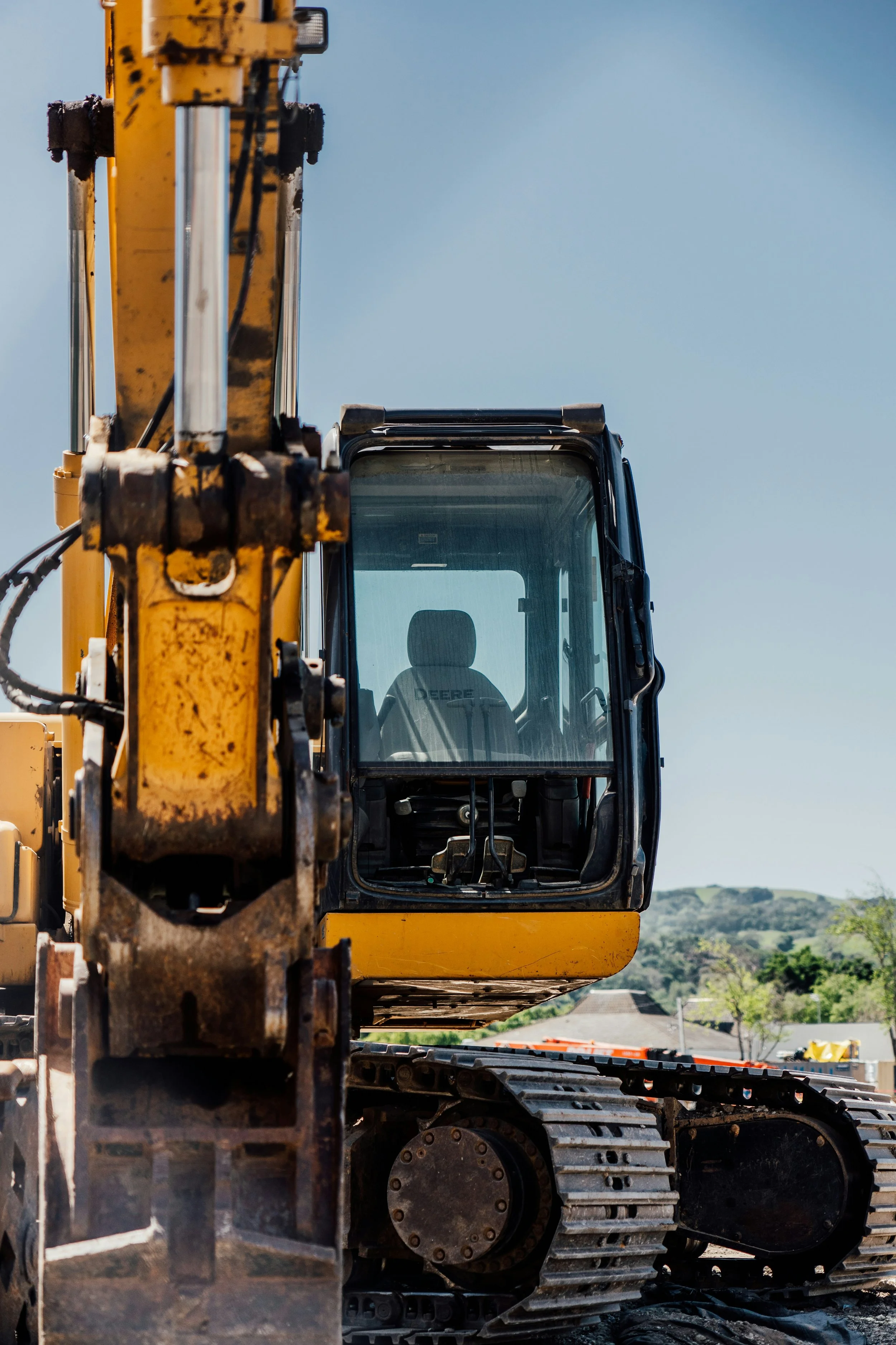 Photo d'une excavatrice jaune avec le bras en avant, vue de face; mécanique mobile sur chantier de construction.