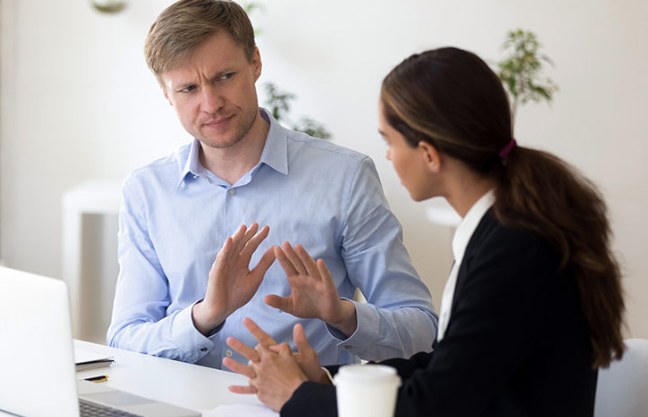 A man and a woman having a serious discussion in an office, the man appears to be resisting change.