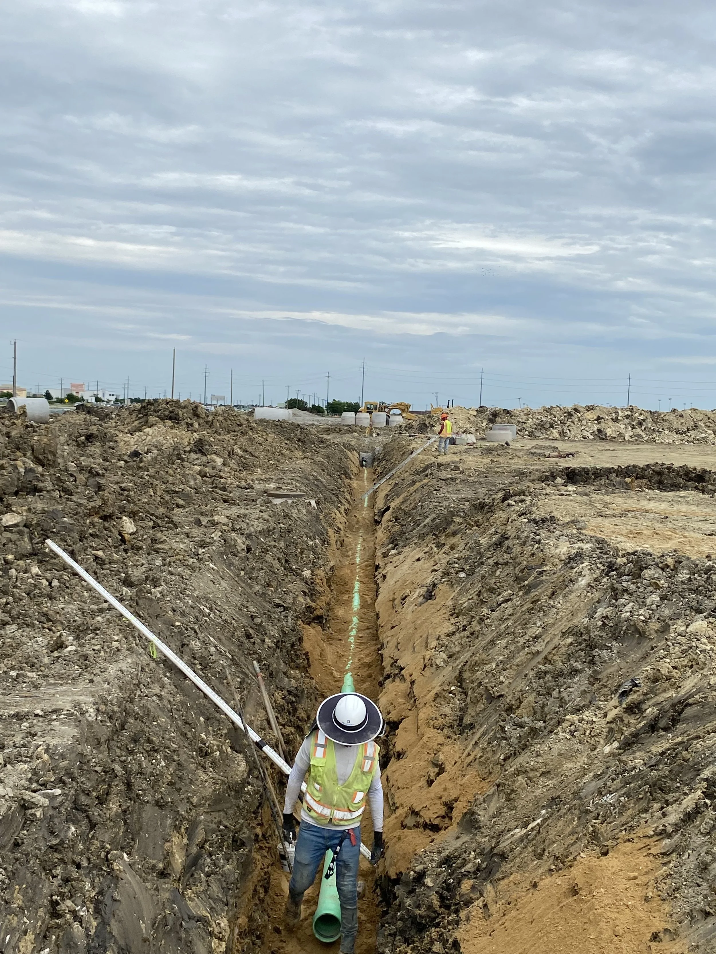 Construction workers install underground pipes in a trench at a construction site