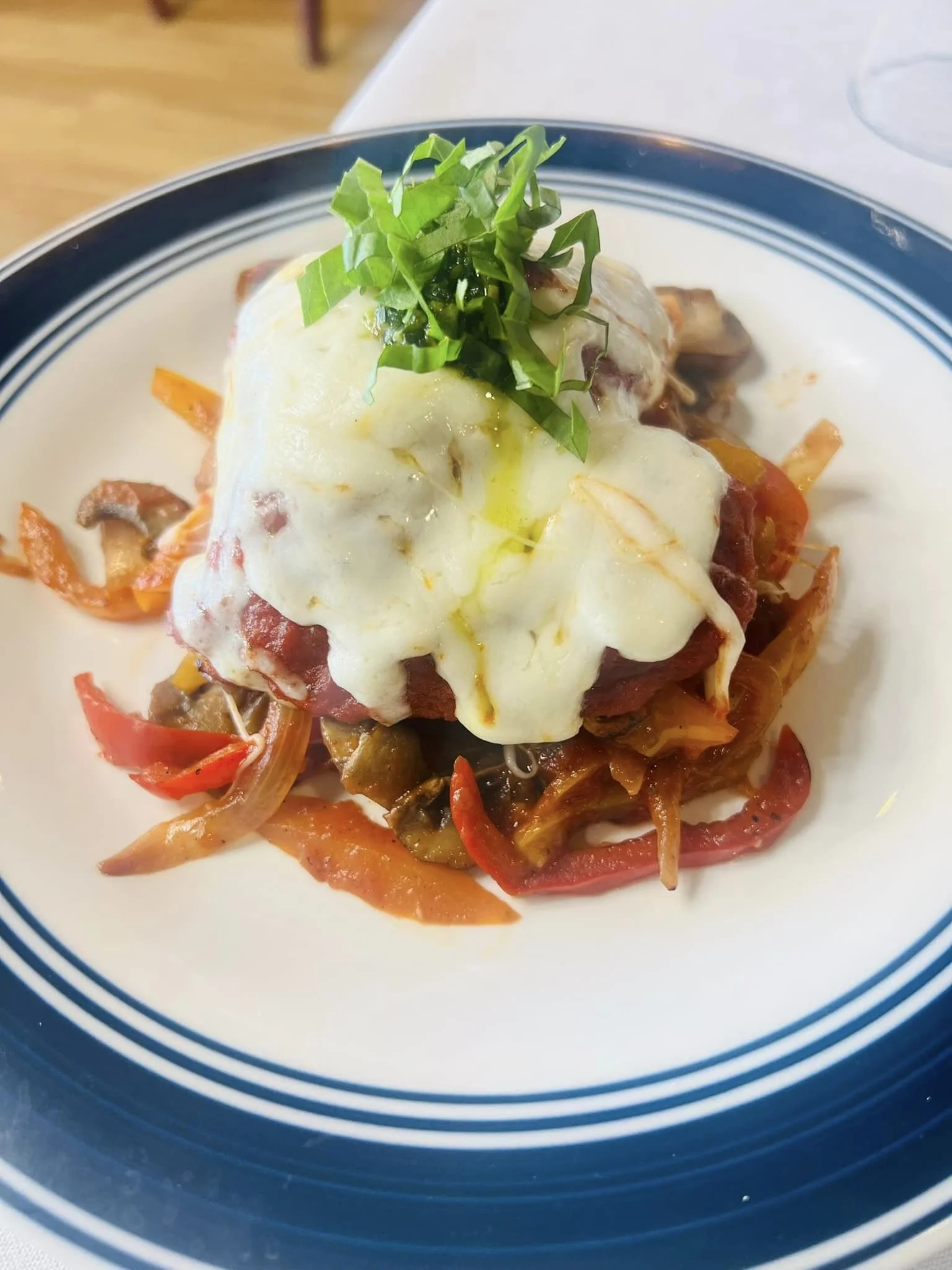A plate of food with a poached egg on top, garnished with chopped green herbs, served over cooked vegetables and meat.