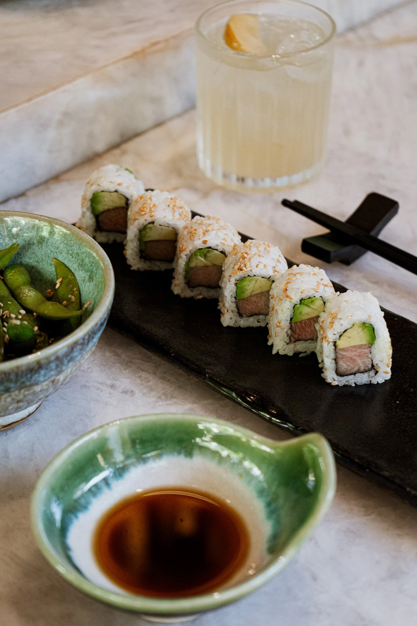 Sushi roll served with soy sauce, edamame, and a citrus cocktail at REMU Tulum.