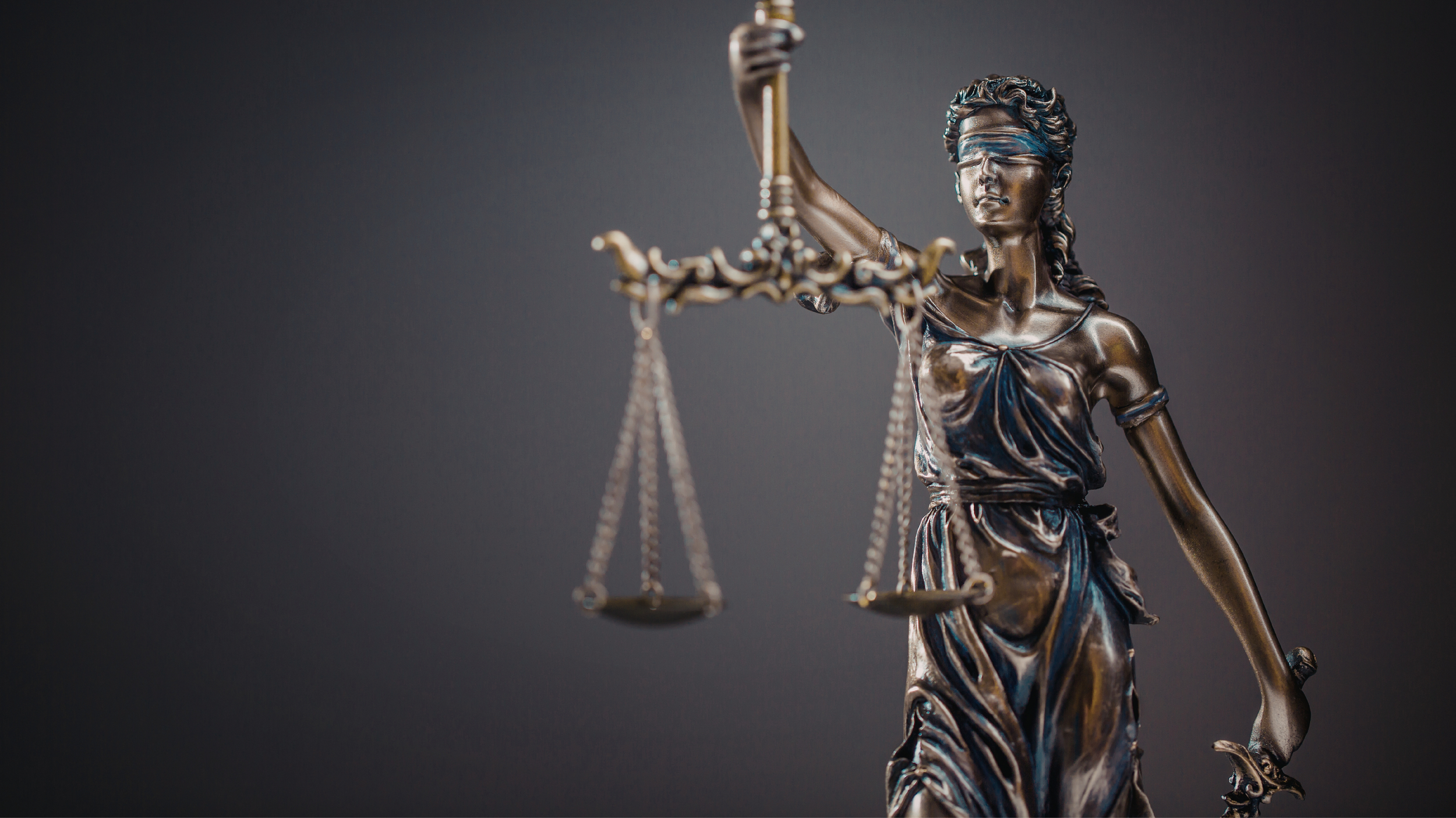 Estatua de la Justicia con los ojos vendados, sosteniendo una balanza y una espada.