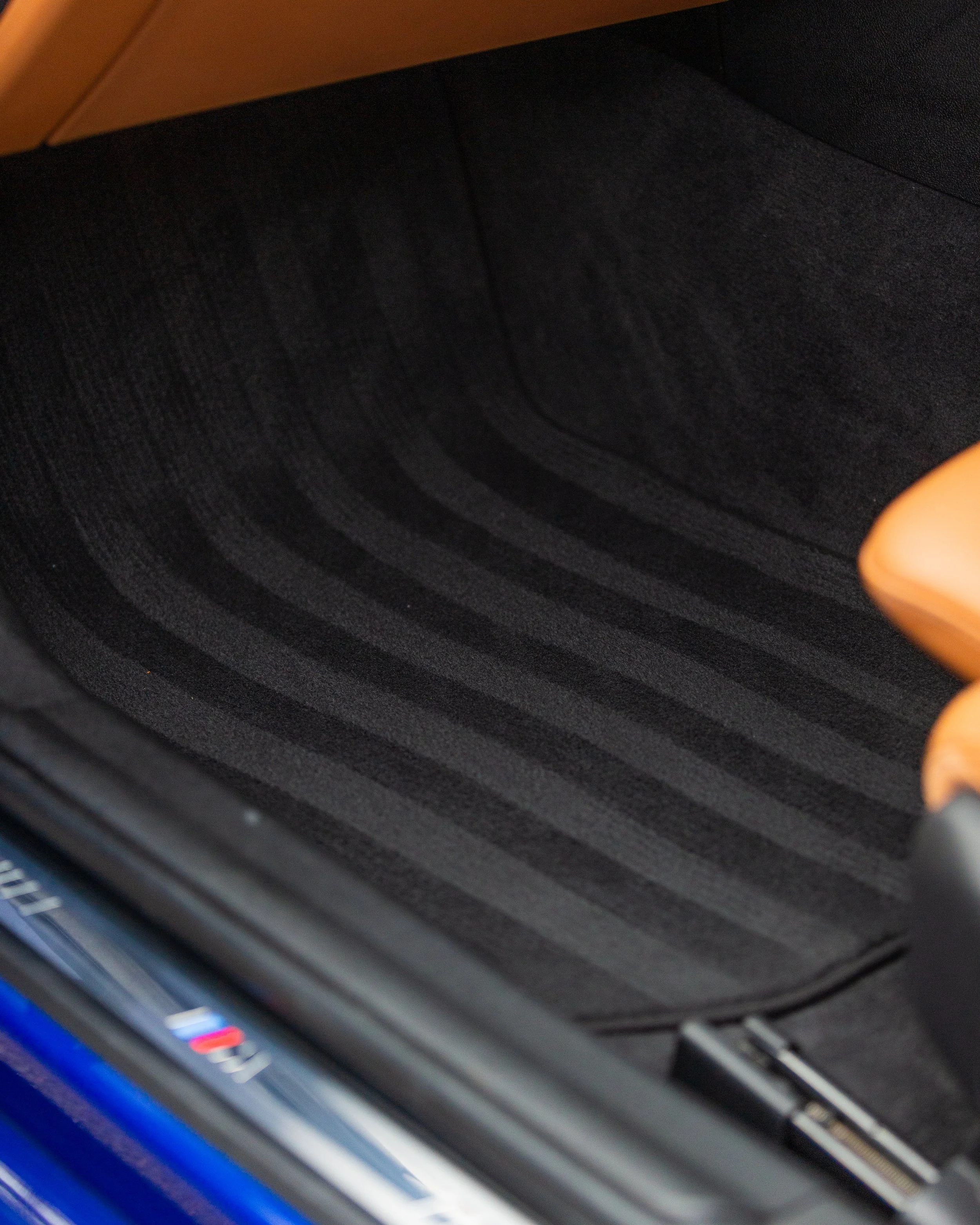 Close-up of a black car floor mat with a textured, striped pattern inside a vehicle.