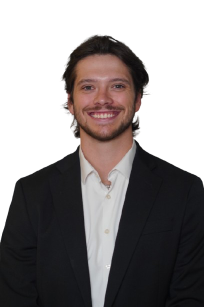A young man with brown hair and a beard, smiling, wearing a black suit jacket and white shirt against a white background.