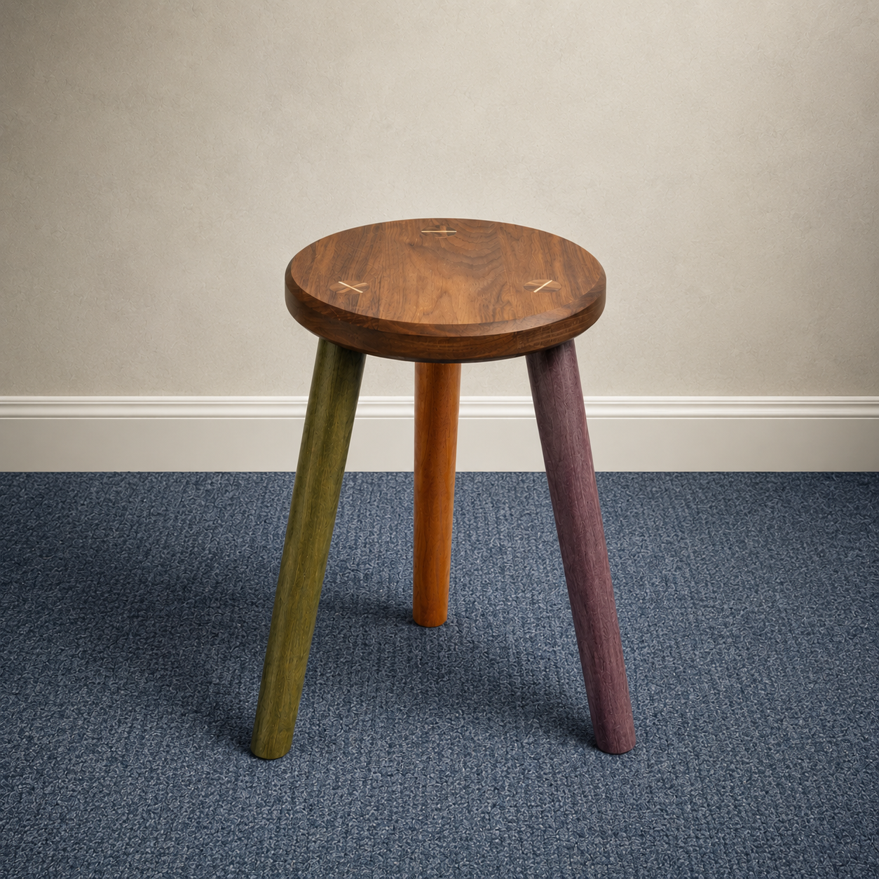 A wooden side table with three colorful legs (green, orange, and purple) placed against a plain wall on a blue carpeted floor.