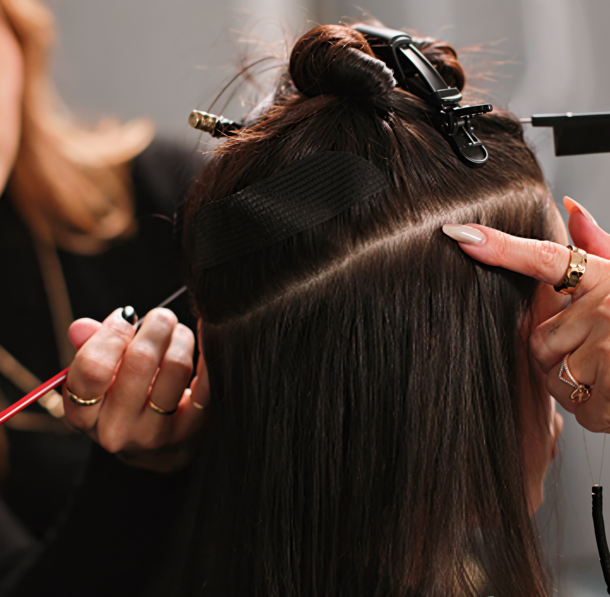 A person is getting their hair curled or styled with hair rollers, and fingers with manicured nails are holding a curling iron or styling tool.