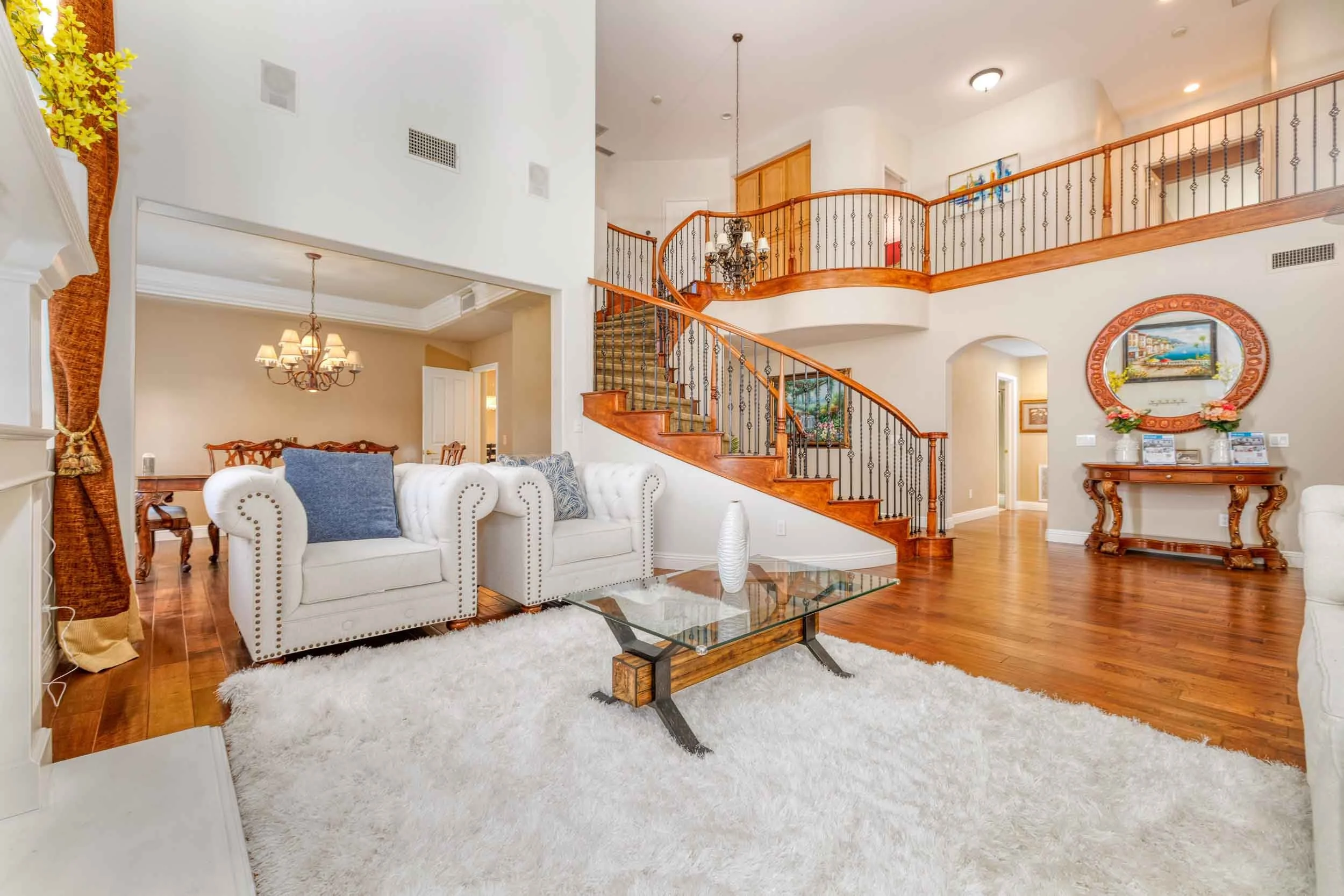 Professional real estate interior photo by Half Full Real Estate Photography — grand two-story foyer with sweeping curved staircase, wrought iron balusters, hardwood floors, and open second-floor landing.