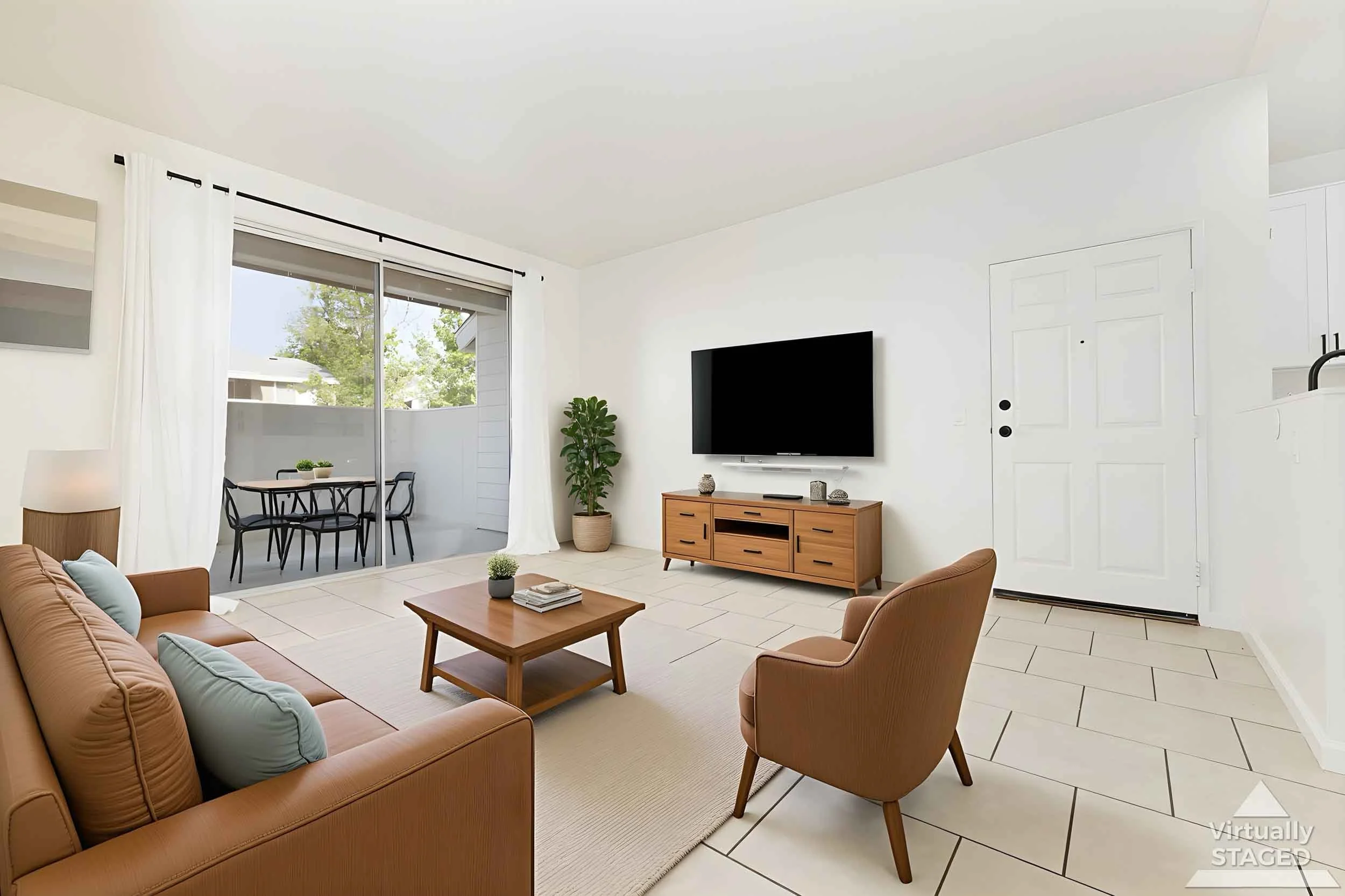 Professional real estate photo by Half Full Real Estate Photography — virtually staged living room with sliding glass door to patio, warm wood furniture, and light tile flooring.