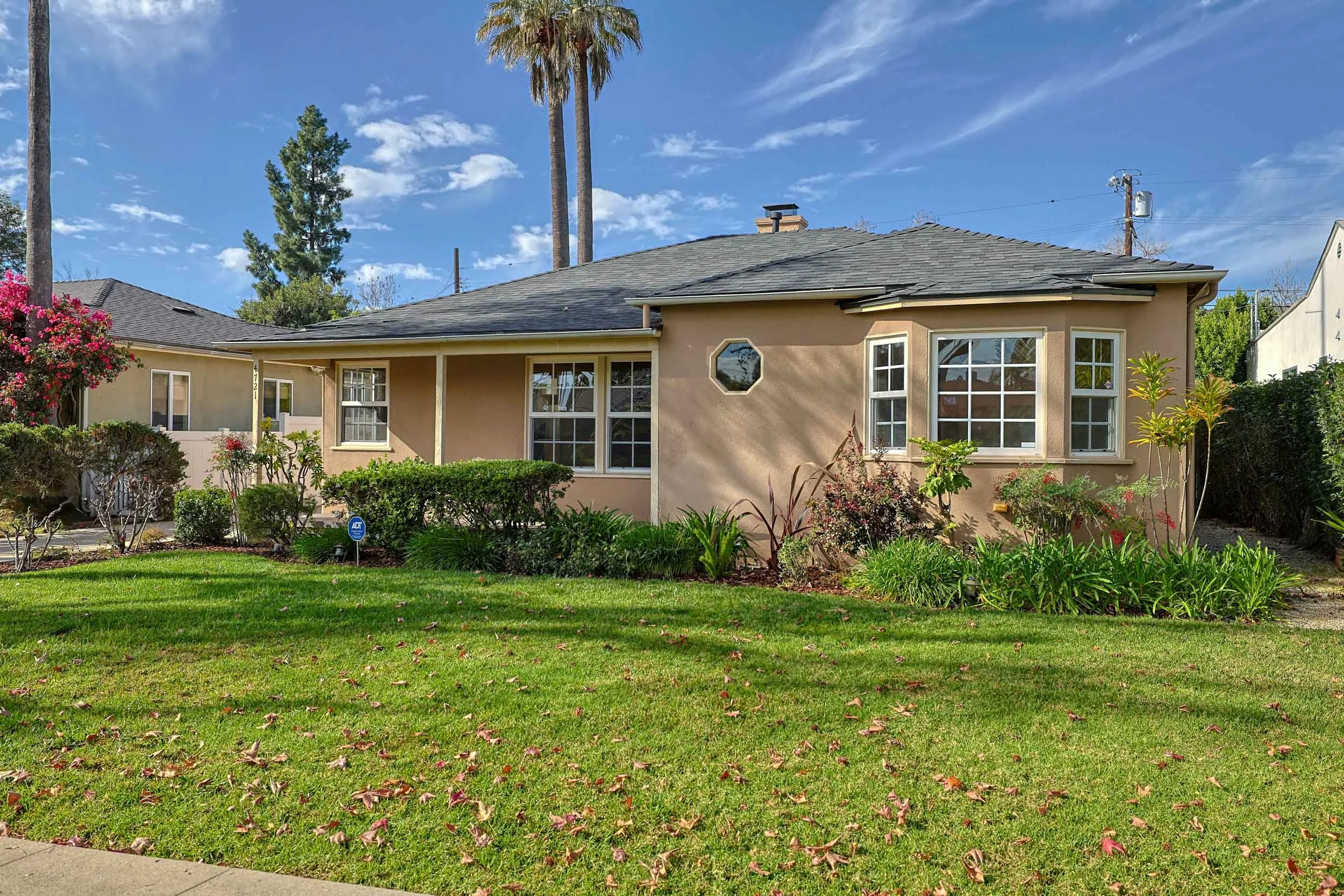 Professional real estate exterior photo by Half Full Real Estate Photography — classic bungalow with lush rose garden, arched trellis, and manicured lawn.