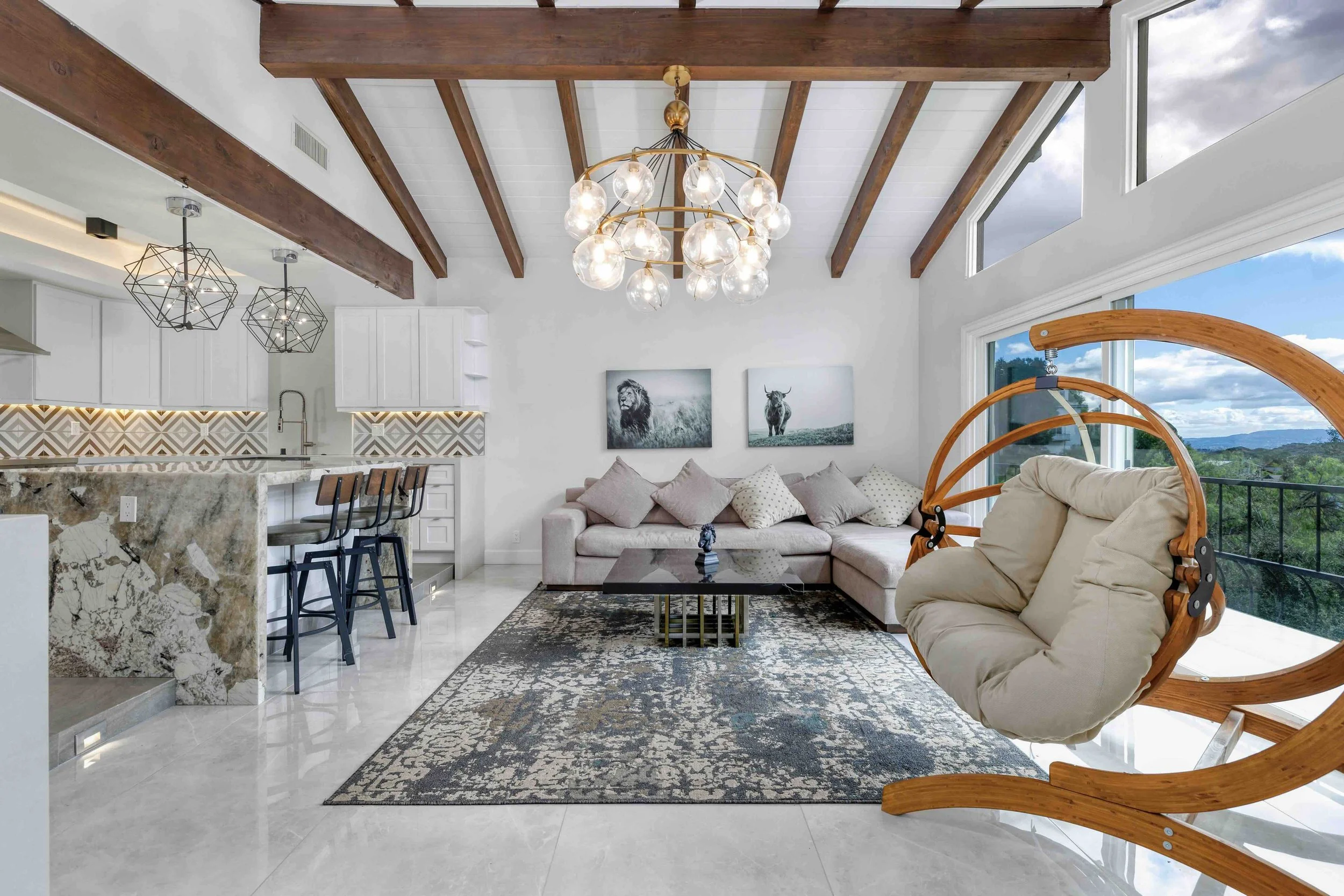 Professional real estate interior photo by Half Full Real Estate Photography — open-concept living room with vaulted wood beam ceiling, statement chandelier, and abundant natural light.
