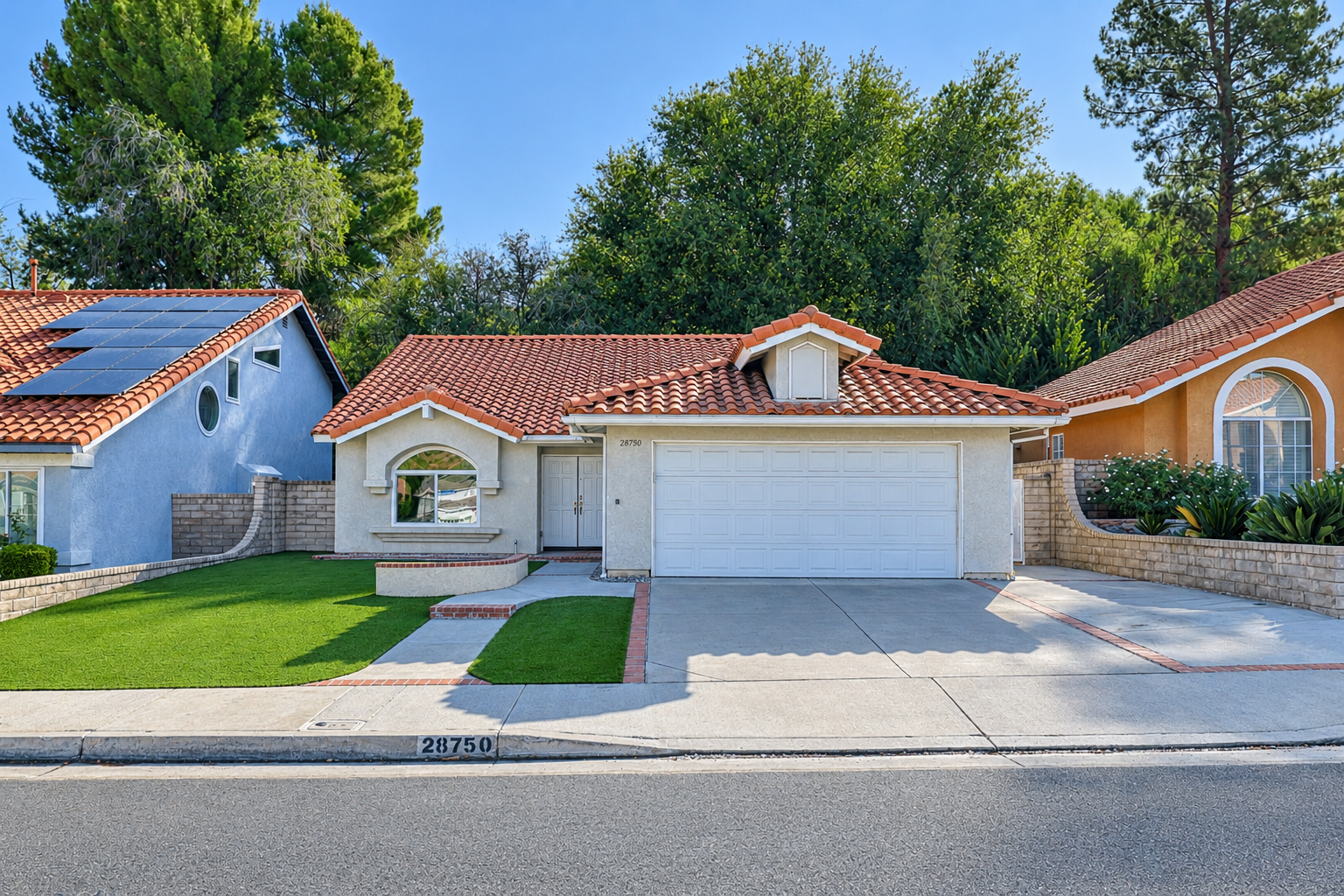 Professional real estate photo of a stucco home with red tile roof, arched window, and brick-edged front walkway