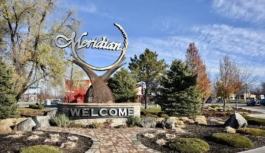 Meridian welcome sign with trees and a partly cloudy sky in the background.