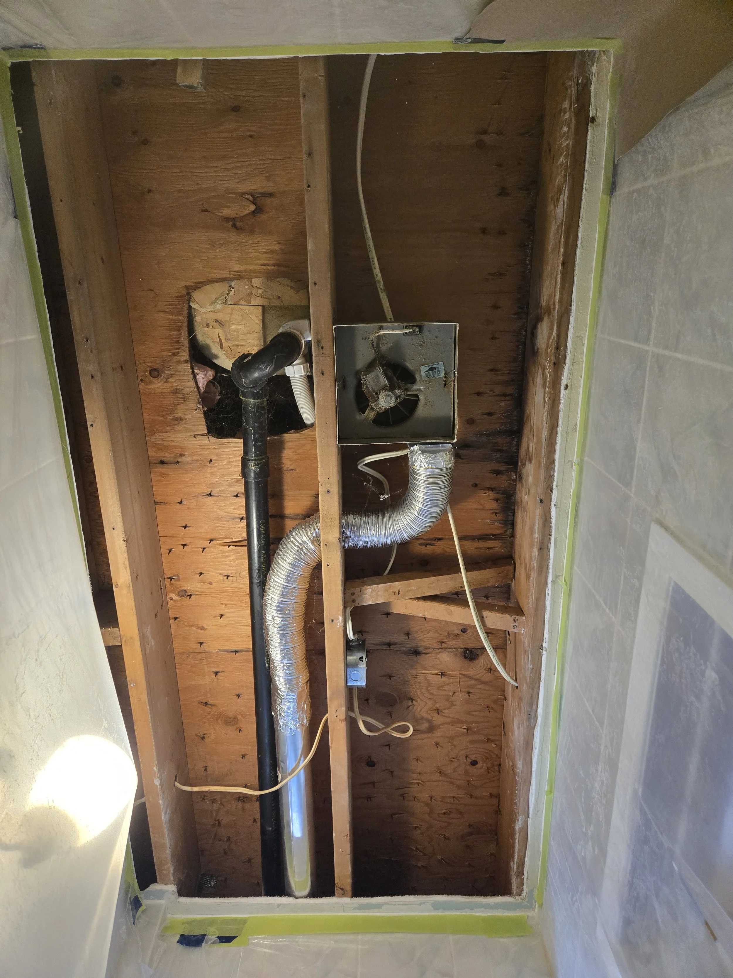 Wooden framing of a room with exposed ductwork, pipes, and electrical wiring, with drywall and wall covers partially installed.